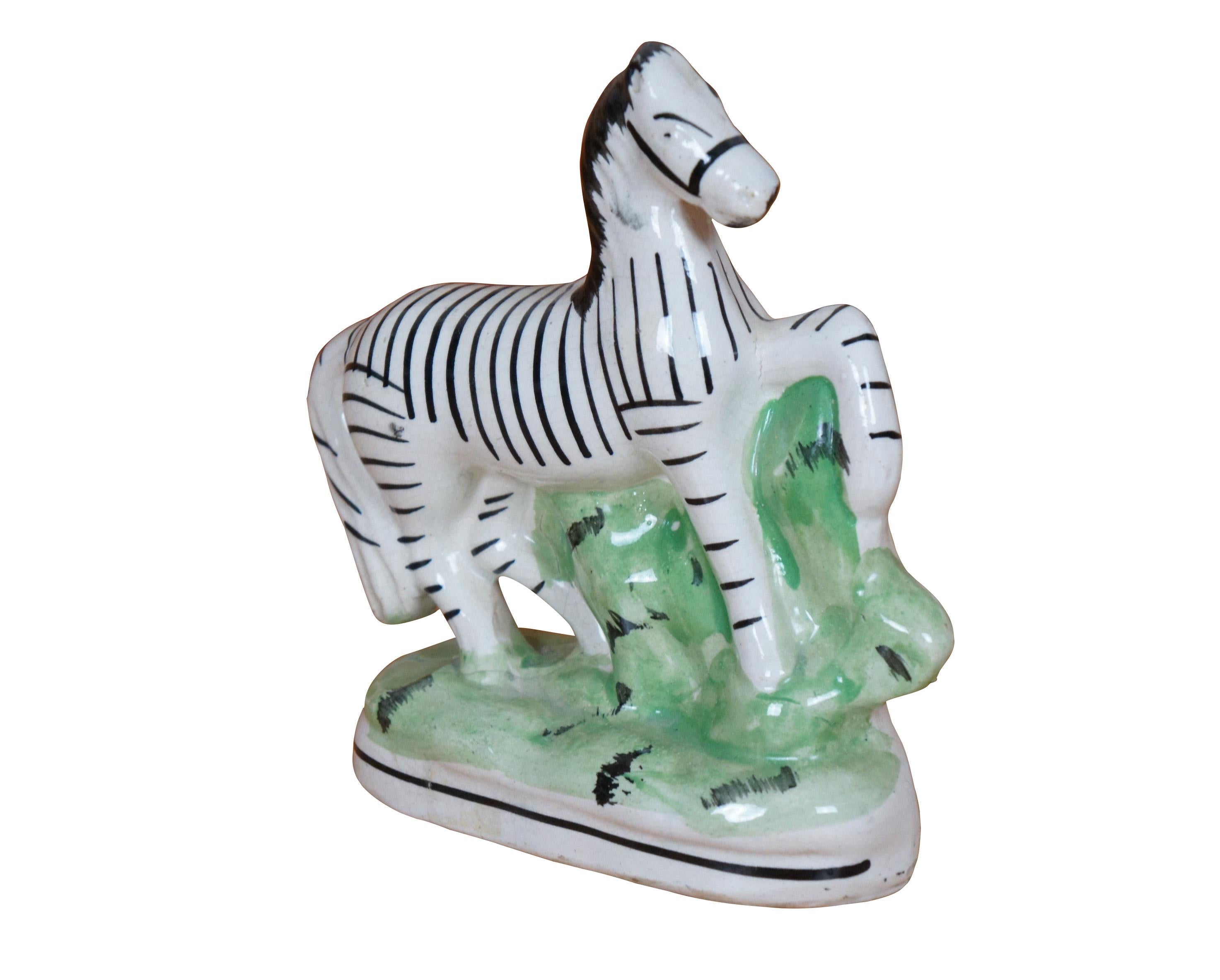 Antique 19th century Staffordshire porcelain flatback figurine in the shape of a horse painted with black stripes to resemble a zebra, prancing on a grassy oval base.

Dimensions:
6.25