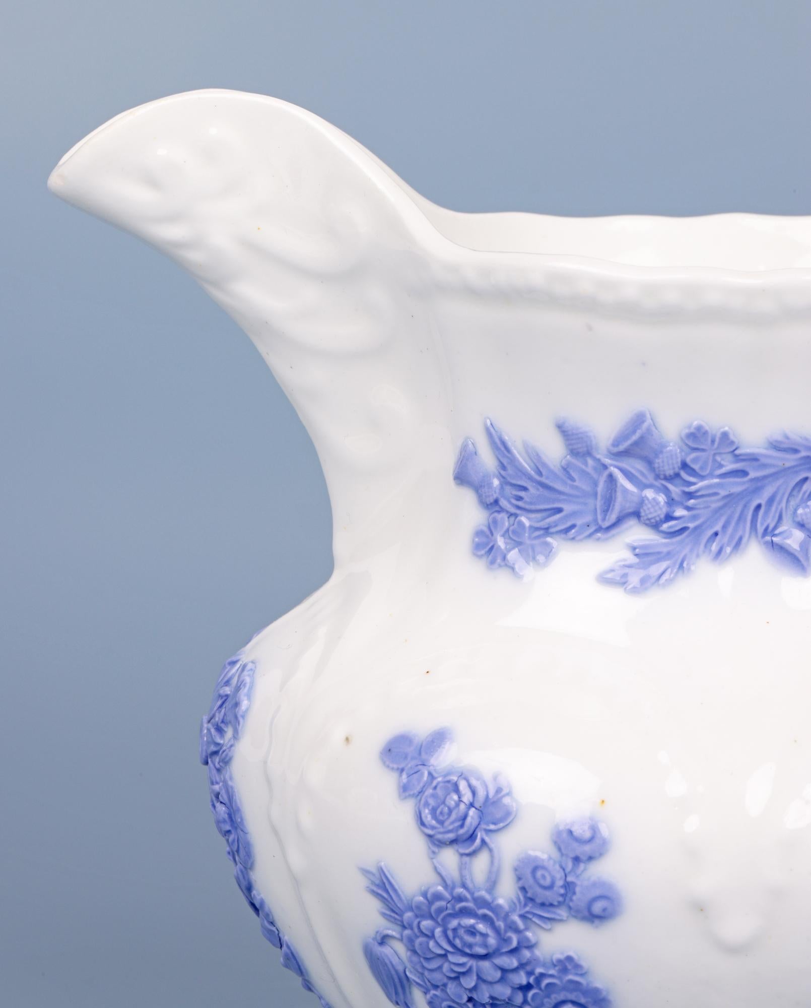 A very fine antique English Staffordshire porcelain jug decorated with lilac sprigged floral designs and dating from around 1830. The jug is finely made in white porcelain and is of rounded shape standing on a narrow round pedestal shaped foot and