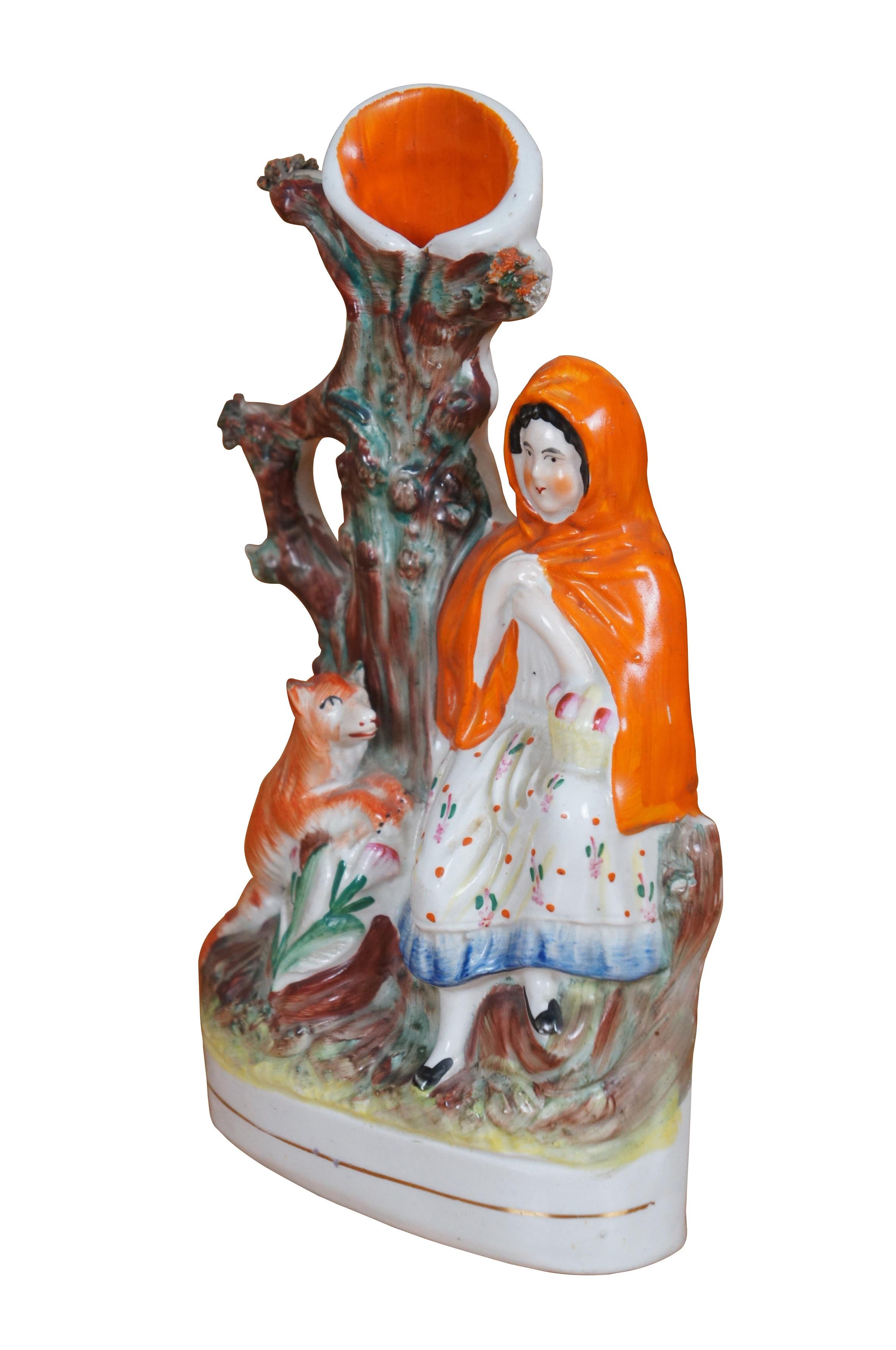 Ancien vase à déversement figuratif à fond plat en porcelaine du Staffordshire du XIXe siècle représentant le petit chaperon rouge et le loup debout près d'un arbre.

Dimensions :
5,5