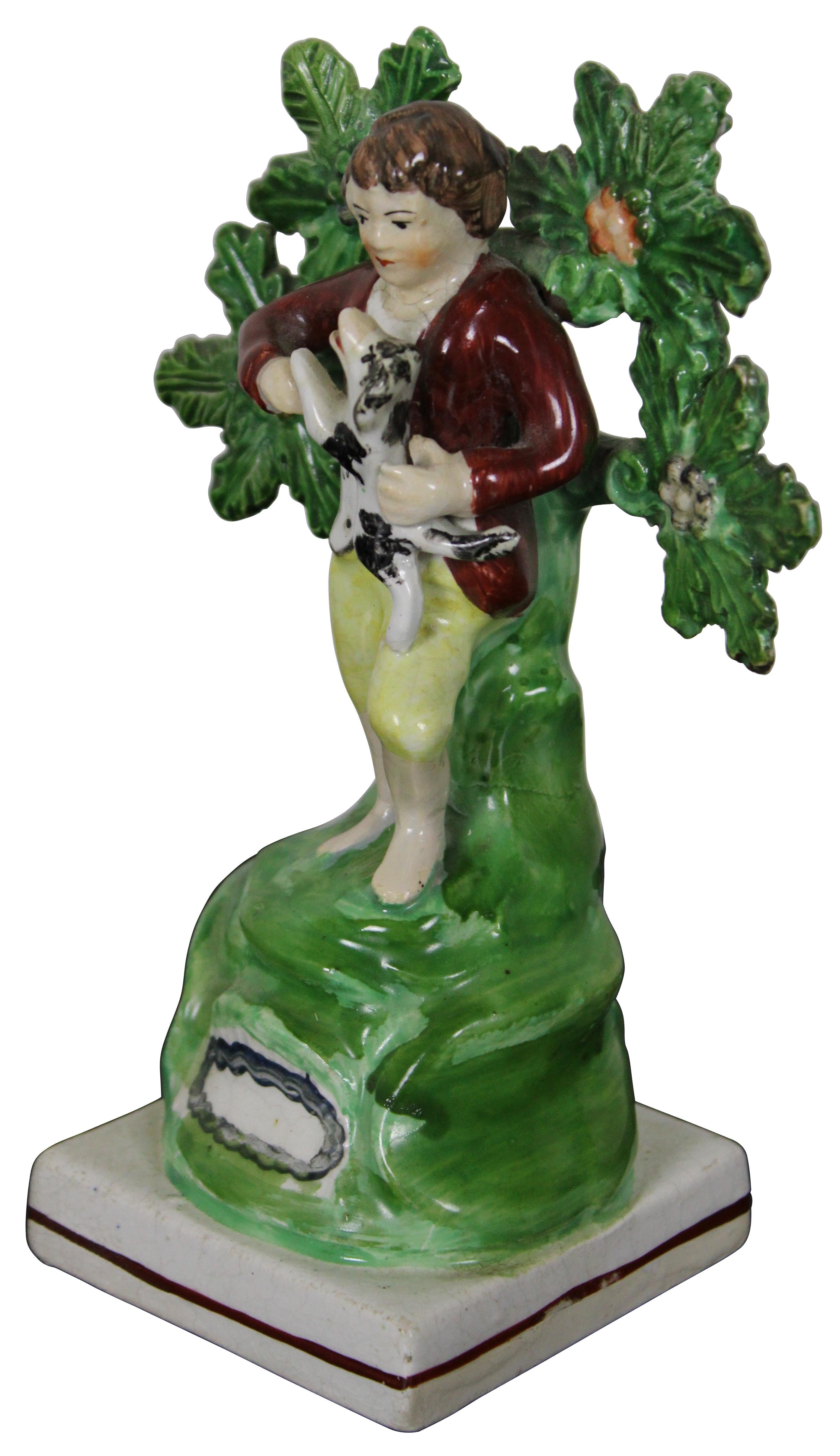 Ancienne figurine victorienne en porcelaine Bocage de Staffordshire en perles de Staffordshire en forme de jeune garçon debout devant un arbre ou un arbuste, tenant un petit chien. Mesure : 5,5