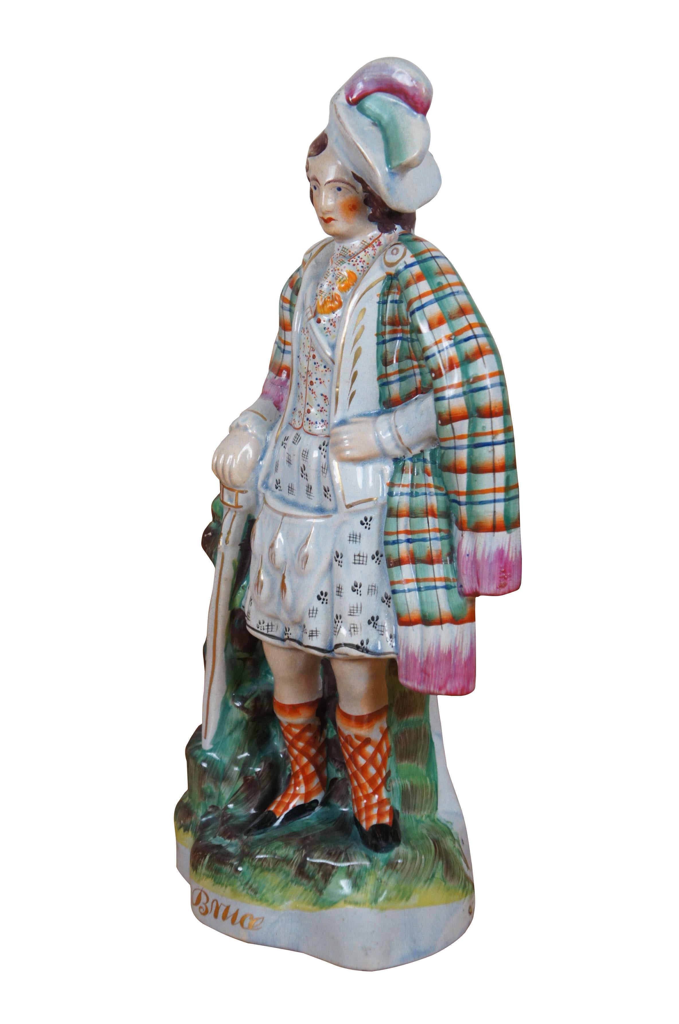 Antique English Staffordshire porcelain figurine in the shape of King Robert I, aka Robert the Bruce (King of Scotland from 1274-1329) standing with a hand on his nip and leaning on a cane or sword and stand of rocks. This brightly painted figure
