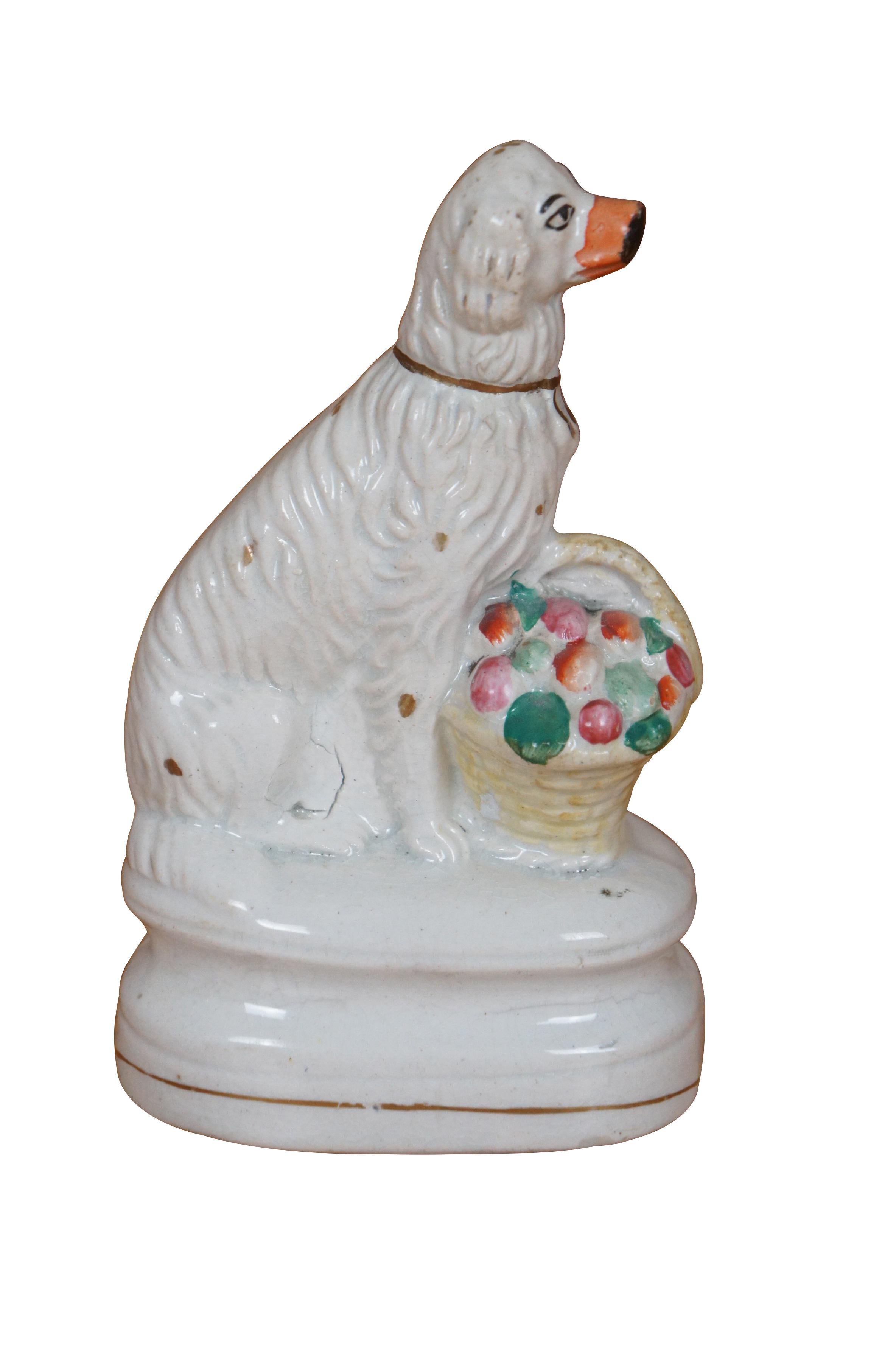 Antigua figura de porcelana de Staffordshire del siglo XIX con forma de spaniel King Charles blanco con nariz roja, sentado con una cesta llena de flores sobre una base oval escalonada.

Dimensiones:
3,75