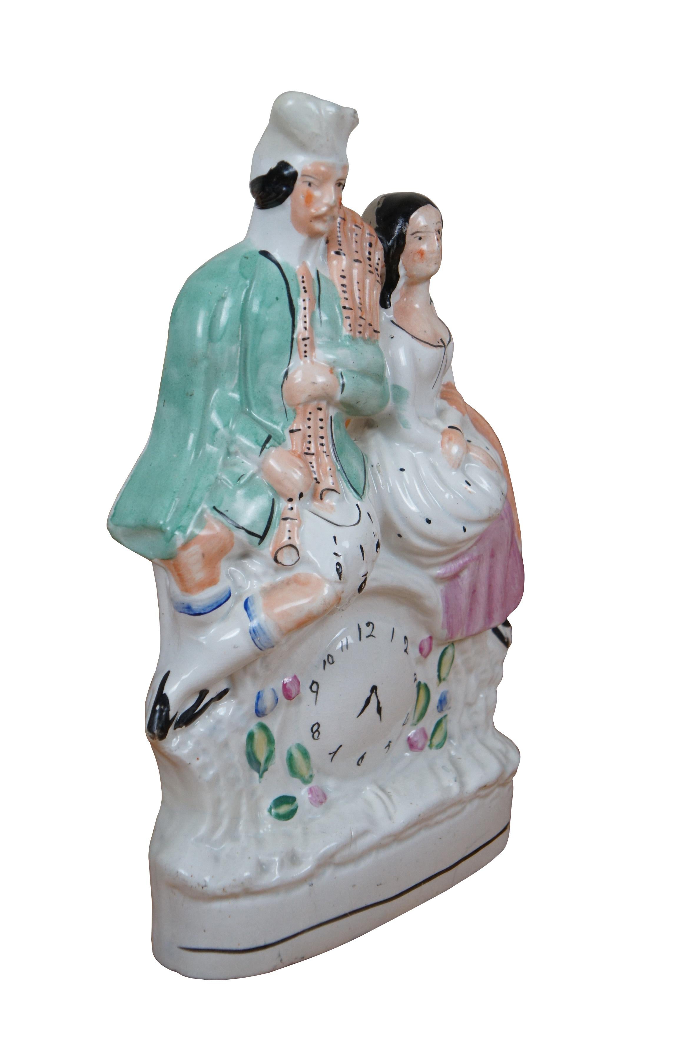 Antigua figurita de porcelana plana inglesa de Staffordshire del siglo XIX que representa a una pareja escocesa de las Highlands encaramada a un reloj floral, que el hombre sostiene un juego de pipas de bolsa.

DIMENSIONES
9