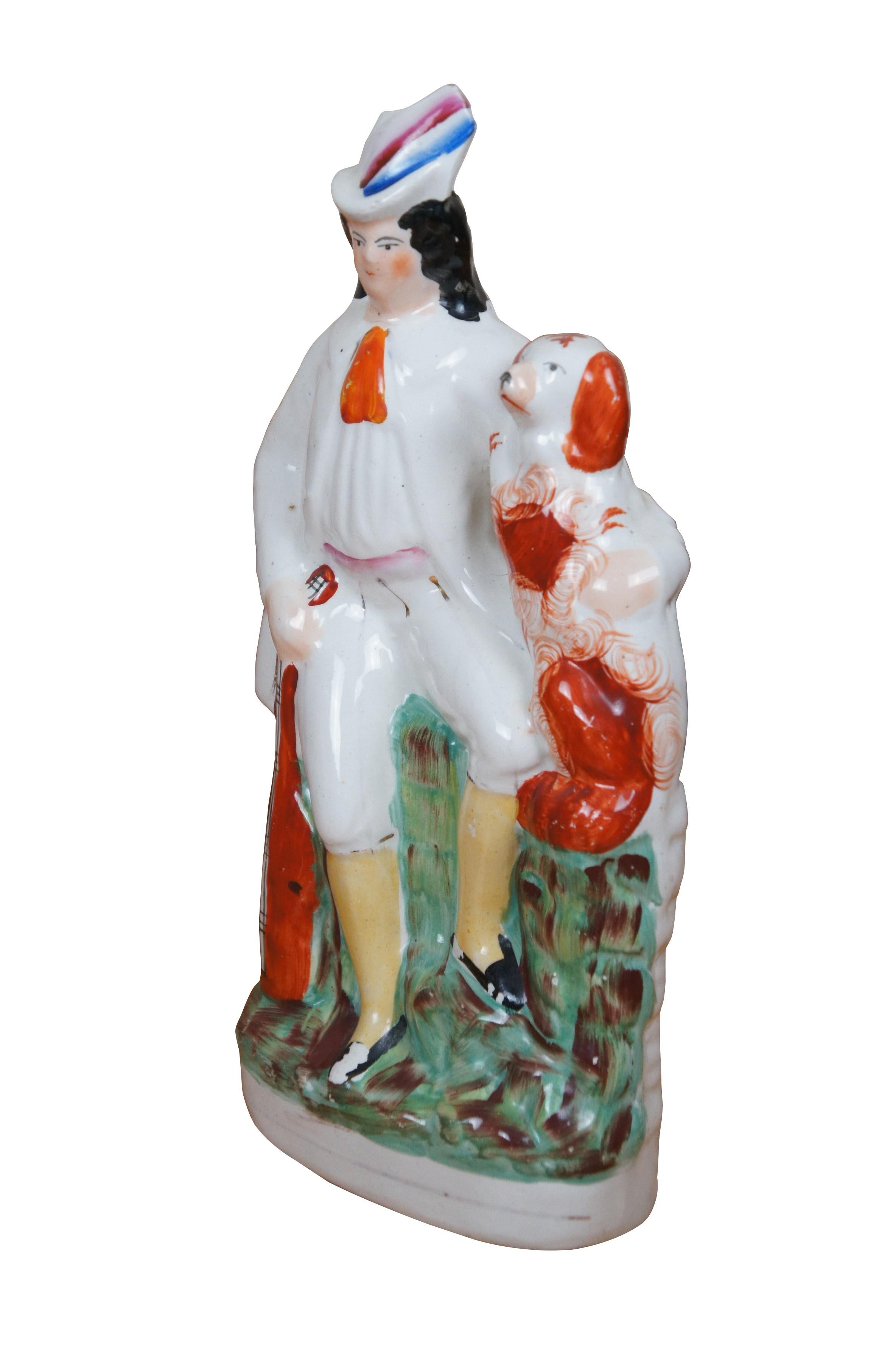 Antica statuetta in porcellana Staffordshire del XIX secolo a forma di uomo / menestrello o trovatore, con in mano una chitarra / strumento a corde, seduto su un muro di muschio con un cane rosso e bianco, un Charles Charles