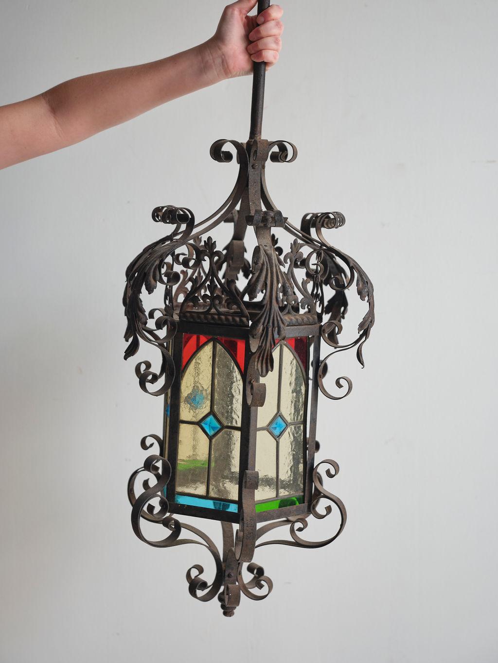 Cette superbe lanterne en fer à vitrail, fabriquée au début du 20e siècle, ajouterait une touche magnifique à n'importe quelle pièce où elle se trouverait. Le vitrail unique et les détails en fer courbé confèrent à cette lanterne un aspect