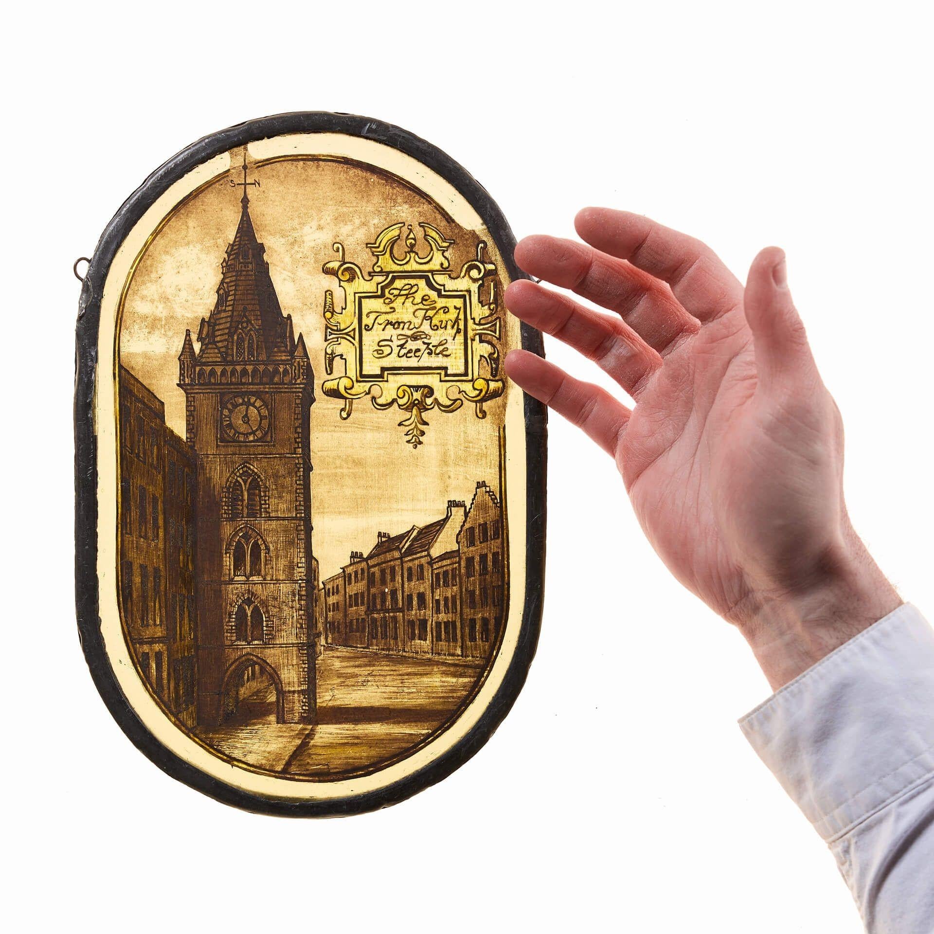 Un interessante e intricato pannello in vetro colorato dipinto a mano alla fine del XIX secolo che raffigura la Tron Kirk di Edimburgo del XVII secolo, uno degli edifici simbolo della città sul Royal Mile. Vendiamo anche un altro pannello dello