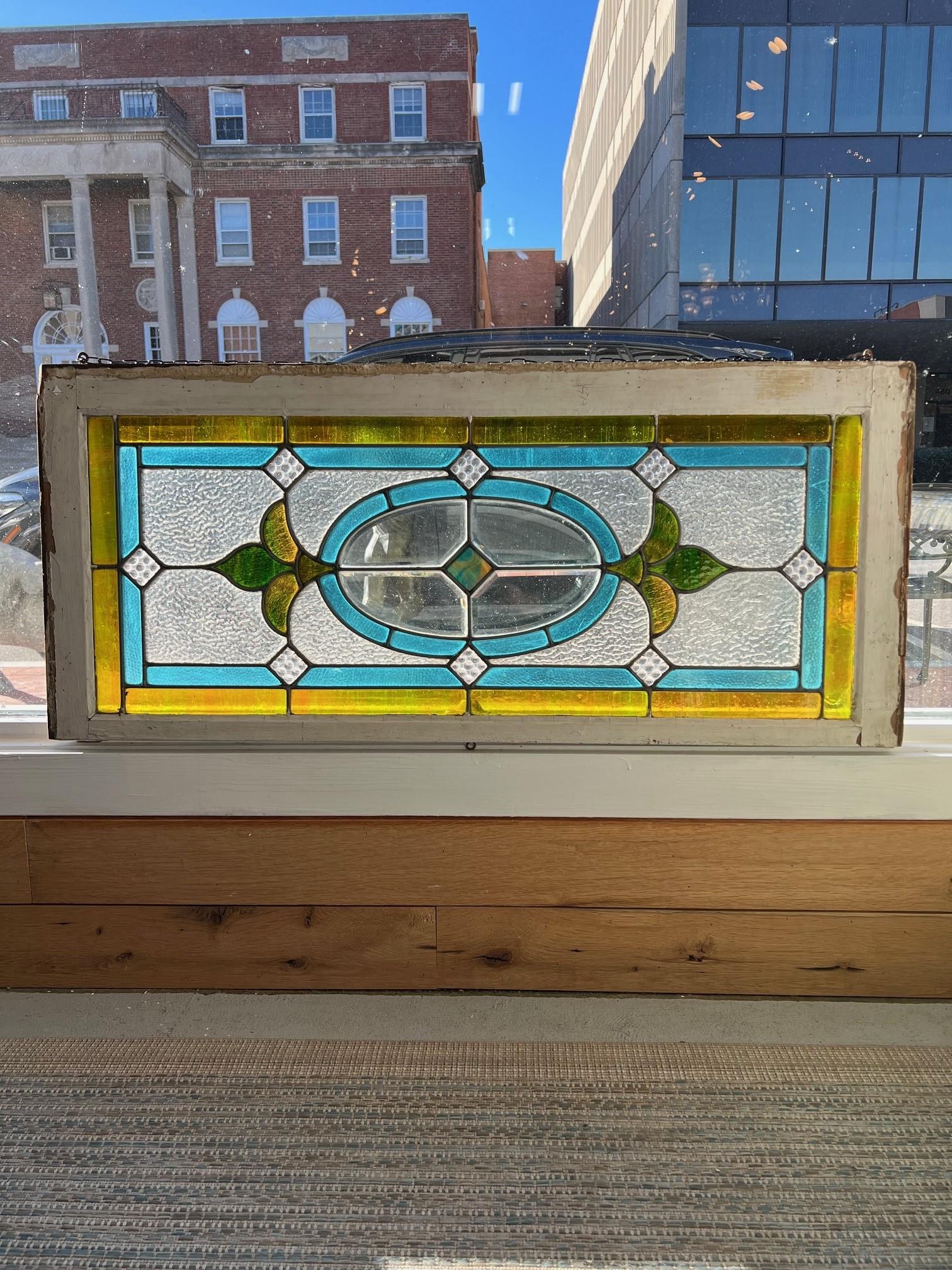 Early 20th Century stained glass window with great colors and a beveled glass center in the original wood frame. This was the better half of a double hung window from a home built in the early 1900s. It's a great window because it works both