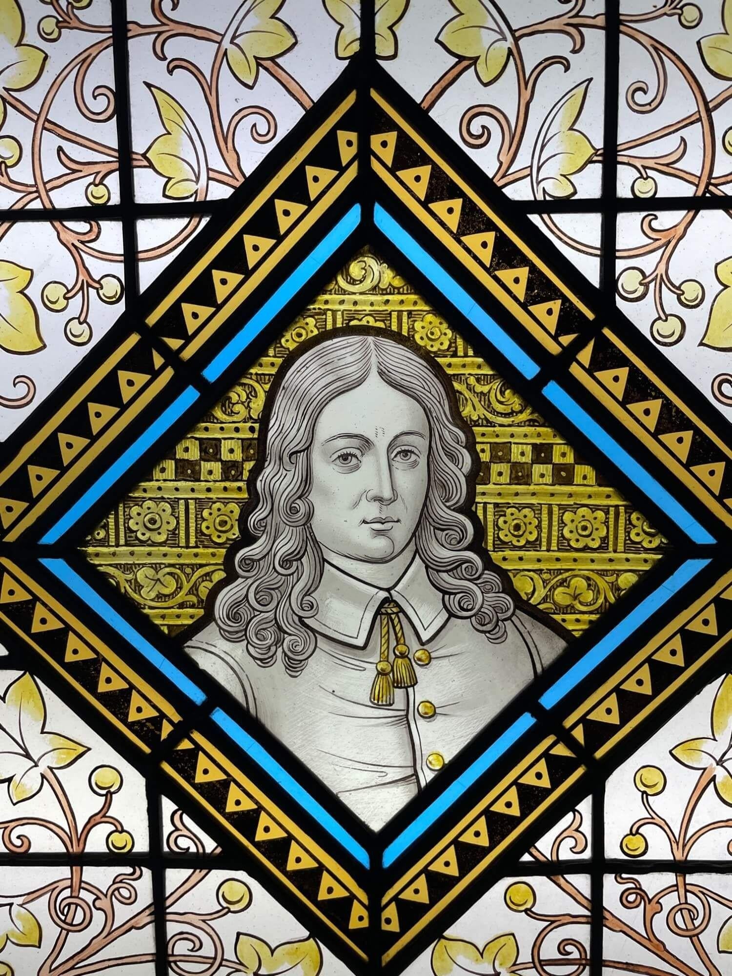 A late 19th century antique stained glass window panel depicting a Victorian figure, one of 3 similar we are selling depicting notable figures of British history. At the centre is an unidentified long-haired subject among scrolling foliage and a