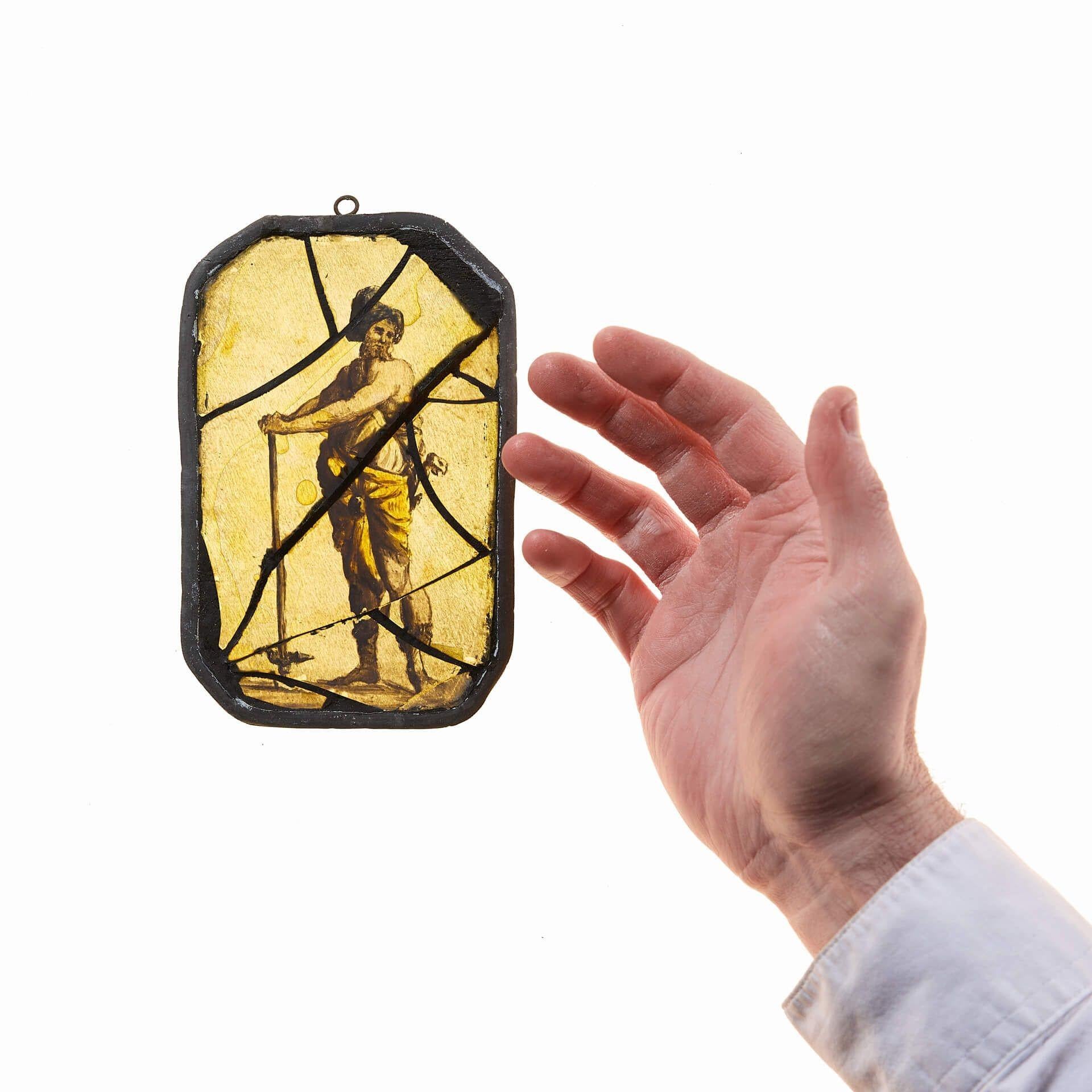 Un vitrail ancien représentant une figure néoclassique censée être un commerçant avec ses outils. Datant d'environ 1780, ce vitrail a résisté à l'épreuve du temps en mettant en valeur la précision, le détail et la bonne qualité de l'artisanat.

Le