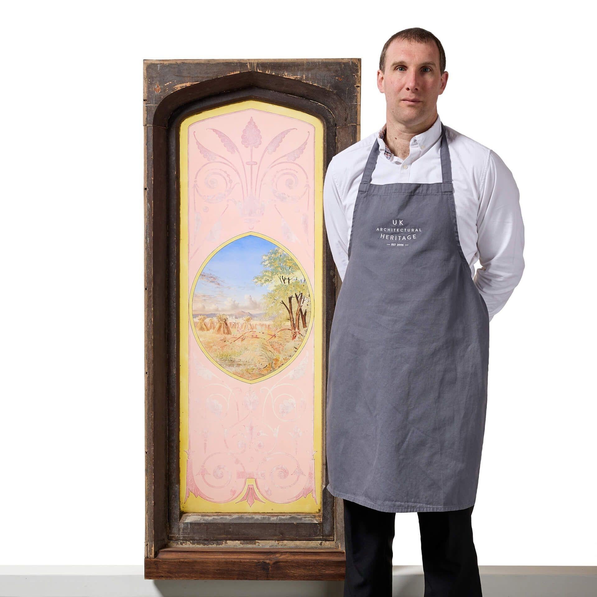 A large antique English stained glass window depicting a English countryside harvest scene, set in gothic pine arch-top frames.

This striking stained glass window showcases a detailed hand painted tranquil scene of the autumn harvest, bordered by