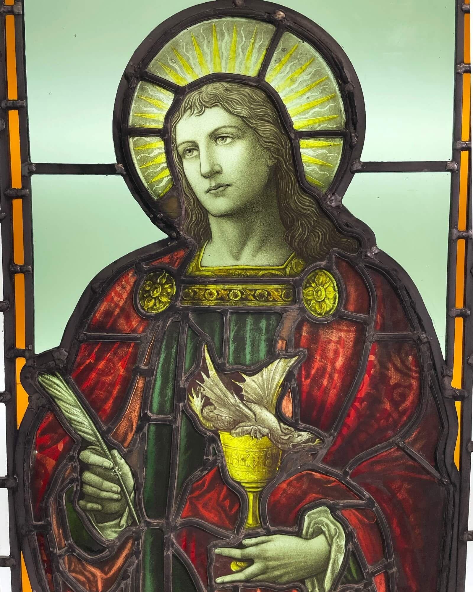 A large and impressive antique stained glass window depicting St John, the Evangelist, dating from circa 1860. In this stunning glasswork piece, the Saint is depicted in vibrant red drapery, a feathered quill in one hand – representing his role as