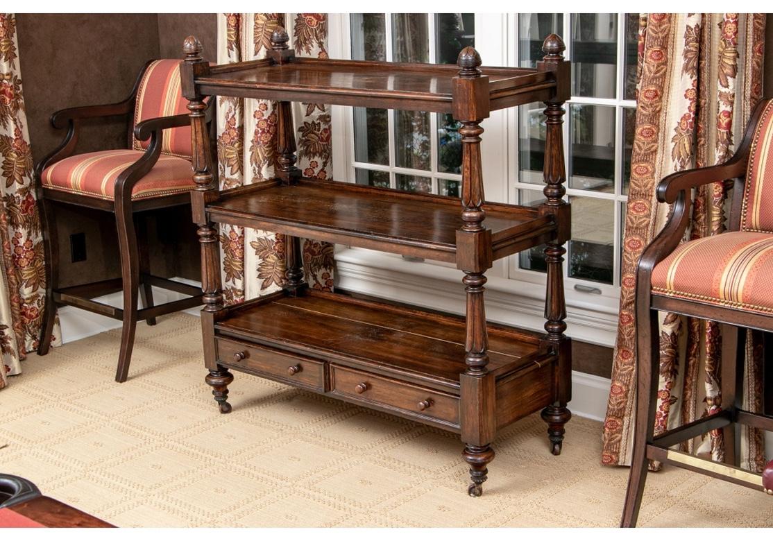 Classic British open étagère with very good construction and fine proportions. Stained oak with 2 shelves, turned and carved corner standards, two shallow drawers, raised on turnip feet with casters.
Dimensions: 51