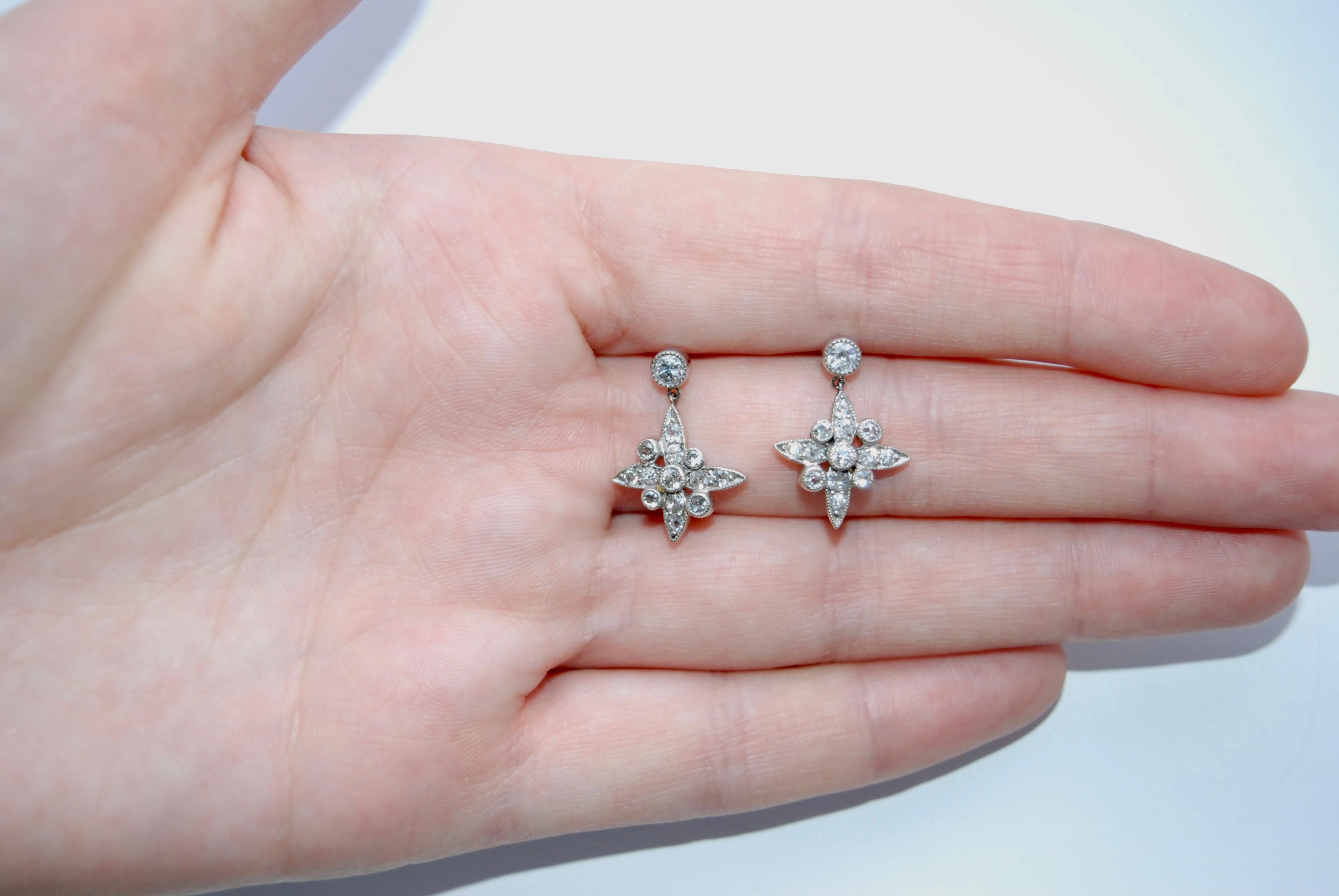 Antique platinum and old cut diamond stud earrings with a suspended star-shaped pendant consisting of four almond-shaped points each containing two diamonds, surrounded by four accent diamonds, all surrounded by milligraining.
Condition: very