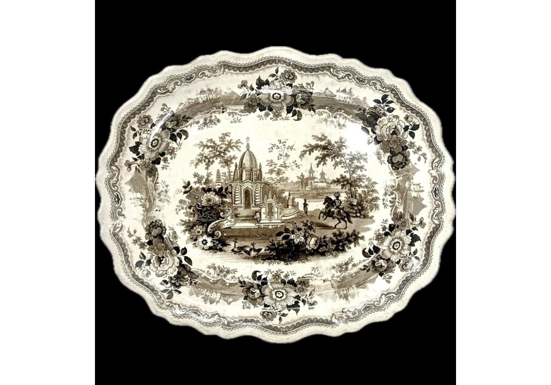 Plat ancien avec transfert en brun d'une scène de guerriers du temple représentant des personnages indigènes avec des bâtiments ressemblant à des temples, un guerrier à cheval à droite. Le plat représentant l'image de l'Inde #7 provient de la base