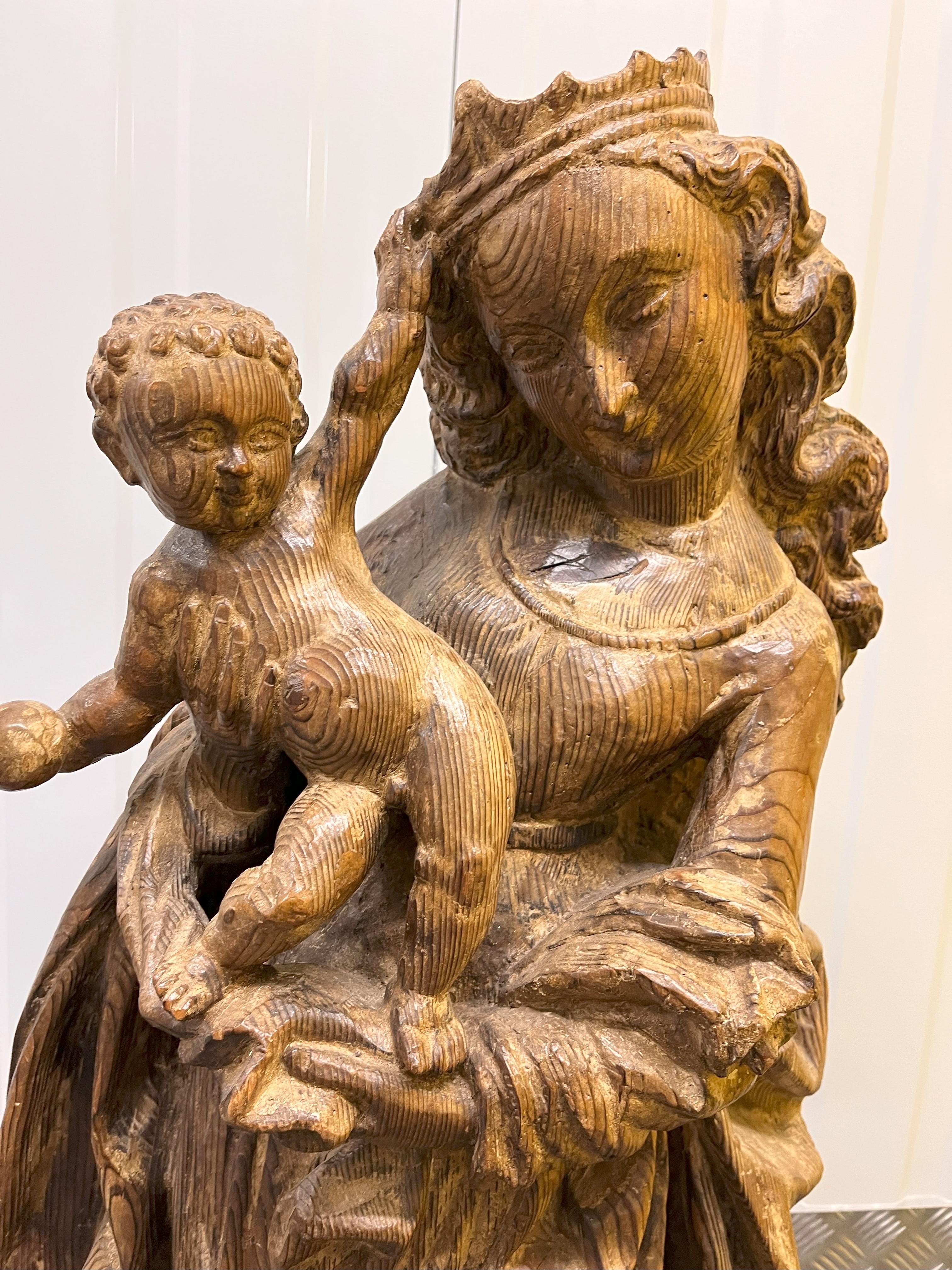 A Pine Carving of Virgin and Child signed E. Lechner. Carved in 15th Century style, a high relief with a hollowed back and depicting the crowned Virgin standing on contrapose with long curly hair flowing down her back and a billowing cloak over a
