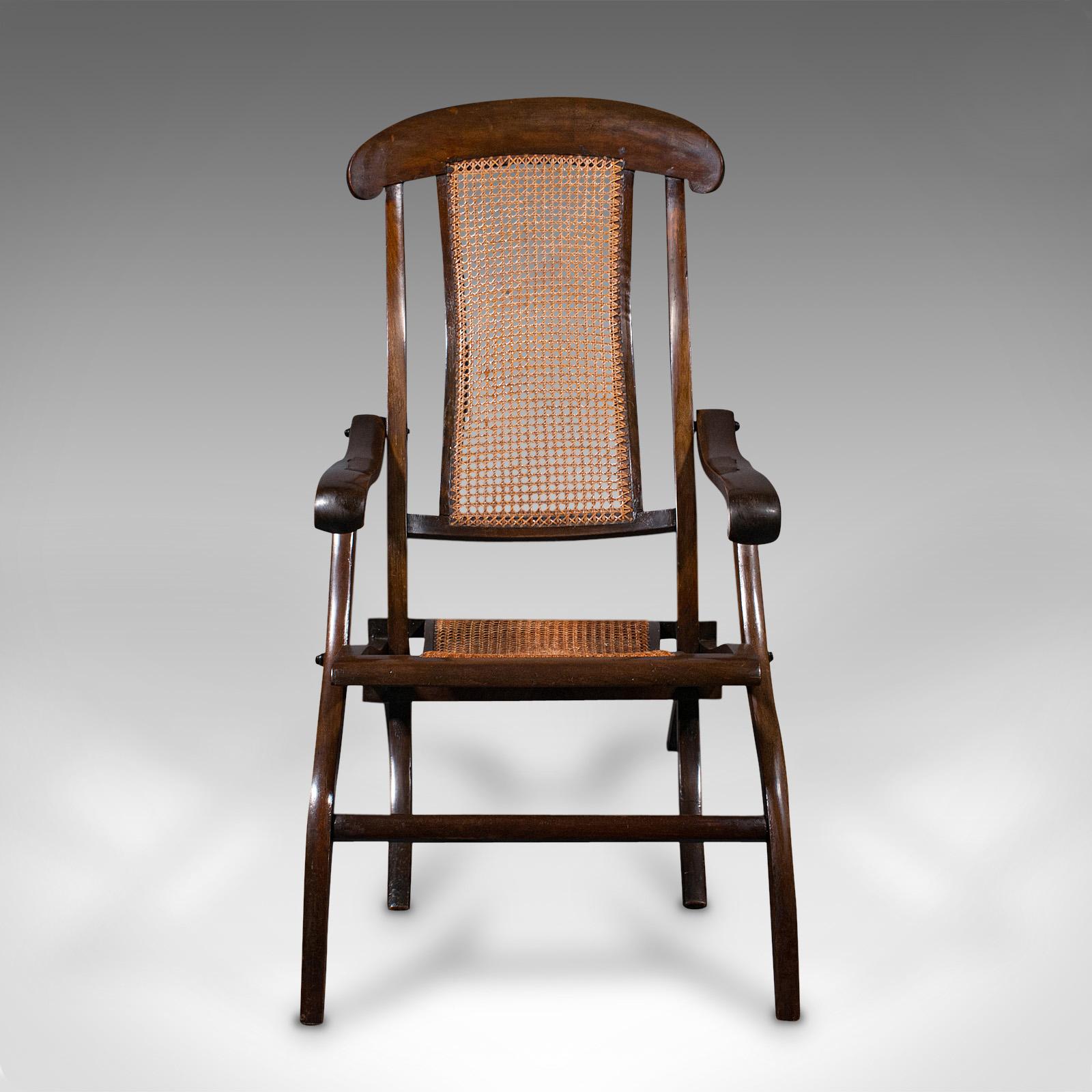 This is an antique steamer deck chair. An English, beech and bergere cane folding armchair or garden lounger, dating to the Edwardian period, circa 1910.

Distinguished form with serpentine, rakish appeal
Displays a desirable aged patina