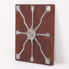 Antique steel lock mechanism mounted on a wooden board.