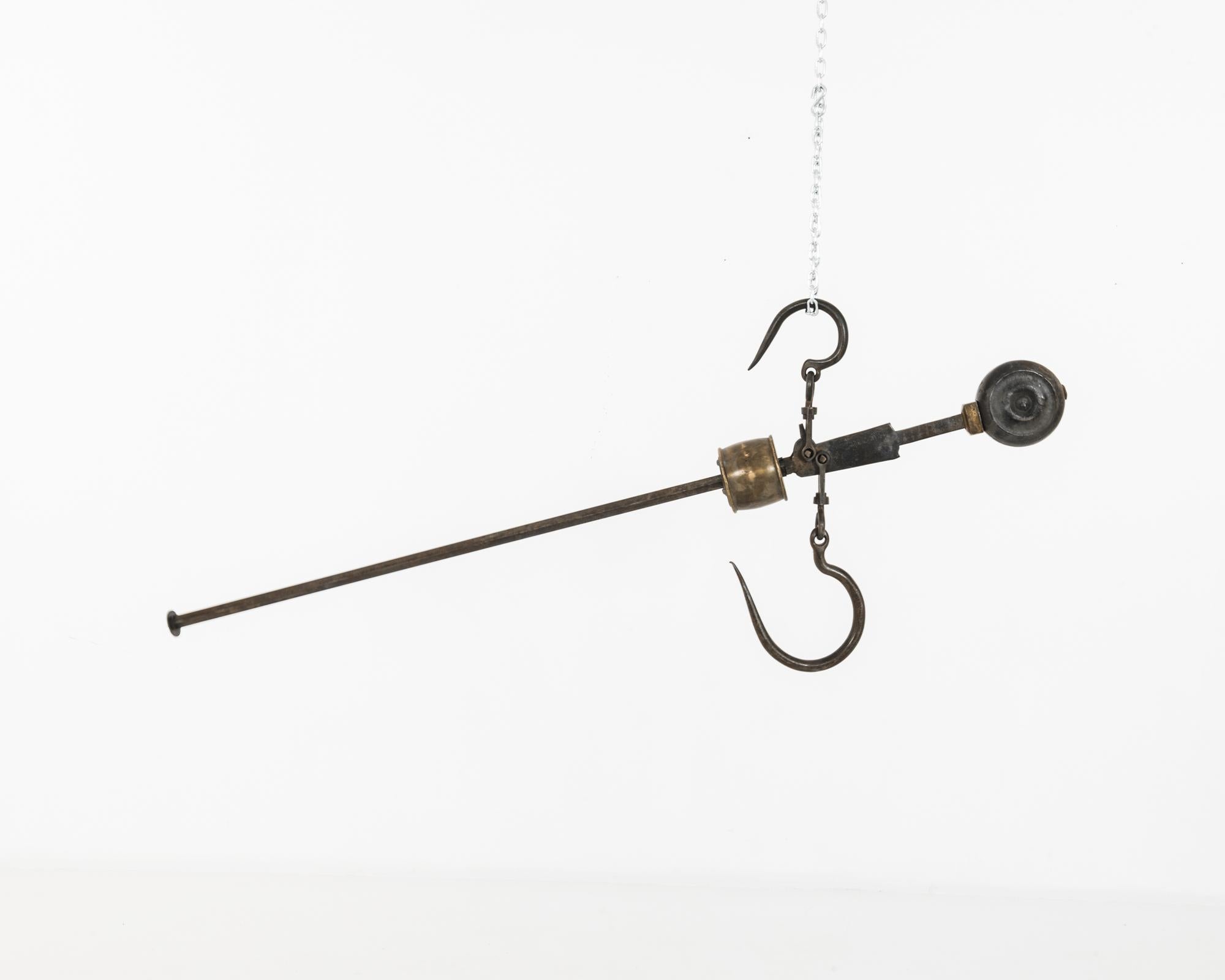 This antique steelyard balance features two hooks and a barrel-shaped cast iron counterweight. One hook would have been suspended from above, with the load hung from the lower hook. The counterweight would be adjusted to balance both arms, and its