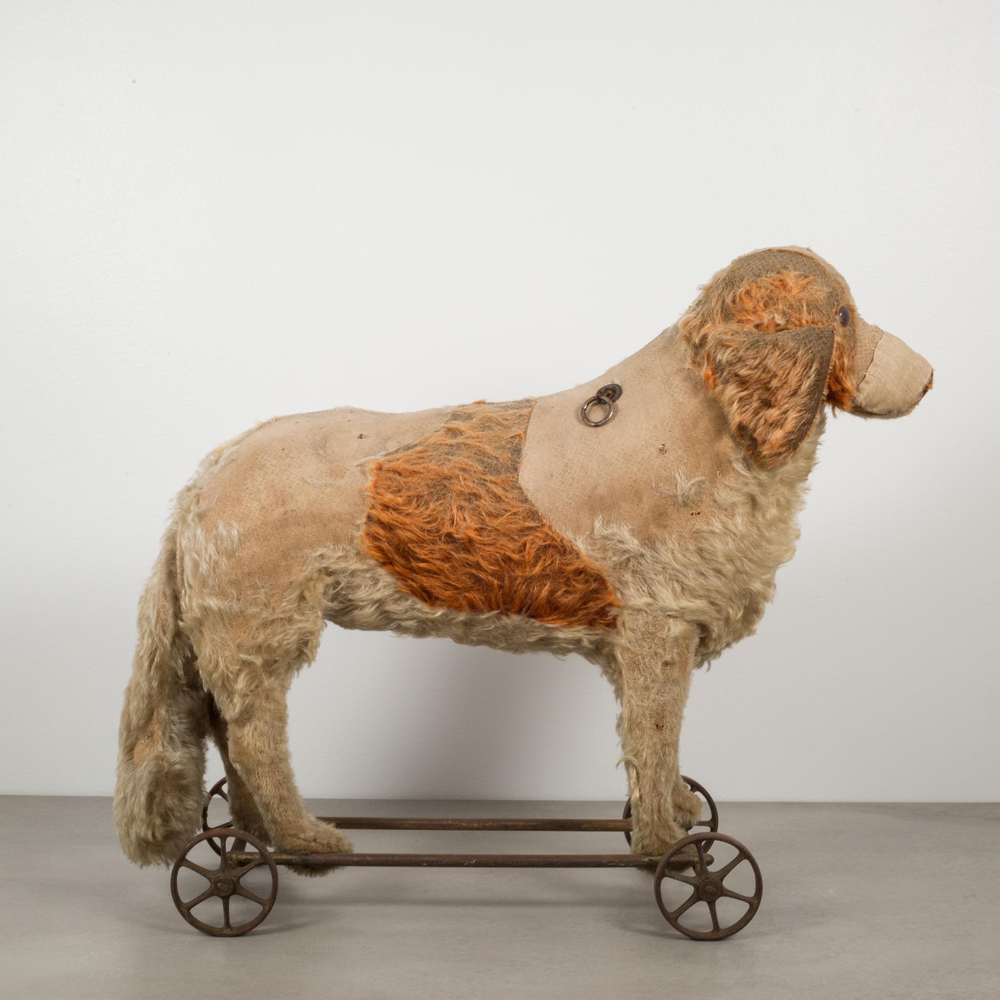 About
This is an original toy dog pull toy made by Steiff. The dog is covered in mohair with glass eyes and stuffed with cotton. The toy stands on a steel frame and steel wheels with a pull chain that makes a sound. This piece is structurally sound