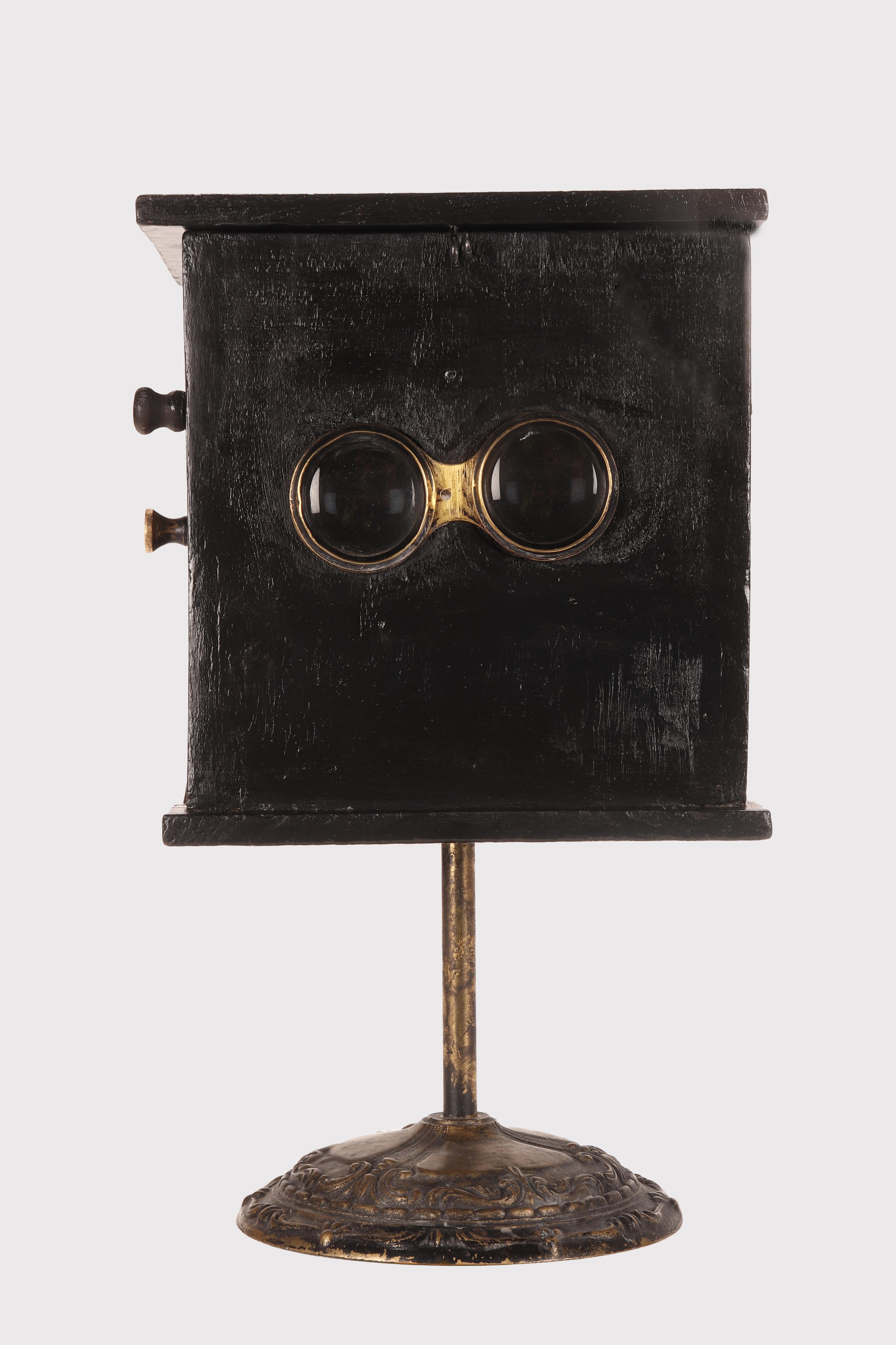 Visionneuse stéréoscopique de table antique utilisée dans les maisons closes pour visionner des images érotiques imprimées sur papier, moyennant paiement. Ce dispositif consiste en un parallélépipède en bois fruitier peint en noir, dont les parois