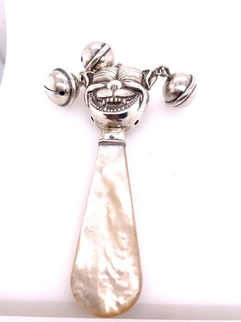 Rare baby rattle:  a grinning jester, with three individual rattles.  Sterling silver, with mother-of-pearl handle.  Double-sided.  
4 1/2