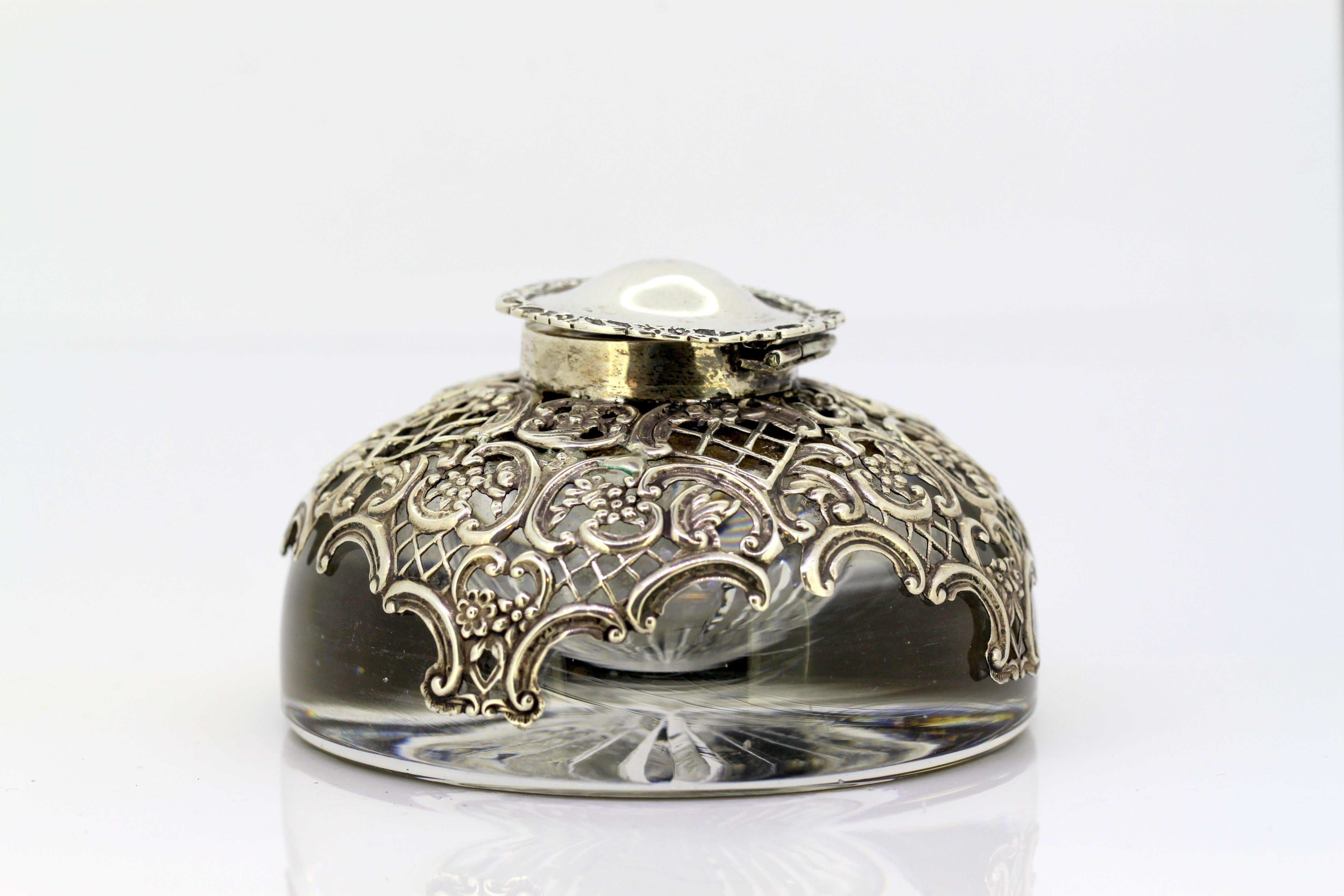 Antique sterling silver and crystal glass ink stand
Maker: William Comyns & Sons
Made in London 1904
Fully hallmarked.

Dimensions: 
Diameter x height: 11.5 x 7 cm
Weight: 1202 grams.

Condition: Item has some surface wear from general