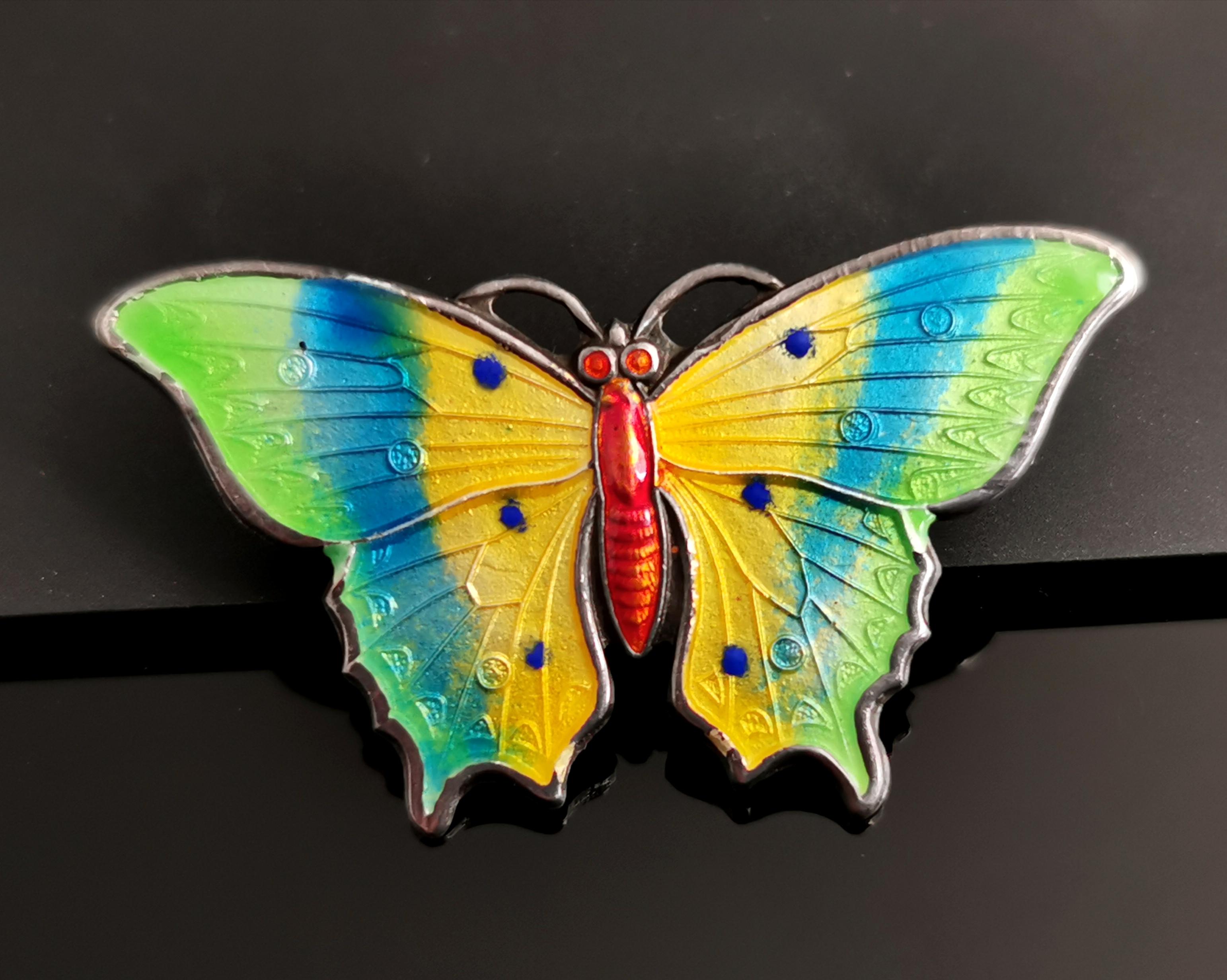 A beautiful and vibrant antique sterling silver and enamel butterfly brooch.

Crafted from solid sterling silver silver and enamelled with bright and vibrant colours of green, yellow and blue with a coral coloured body.

It has an old C type clasp