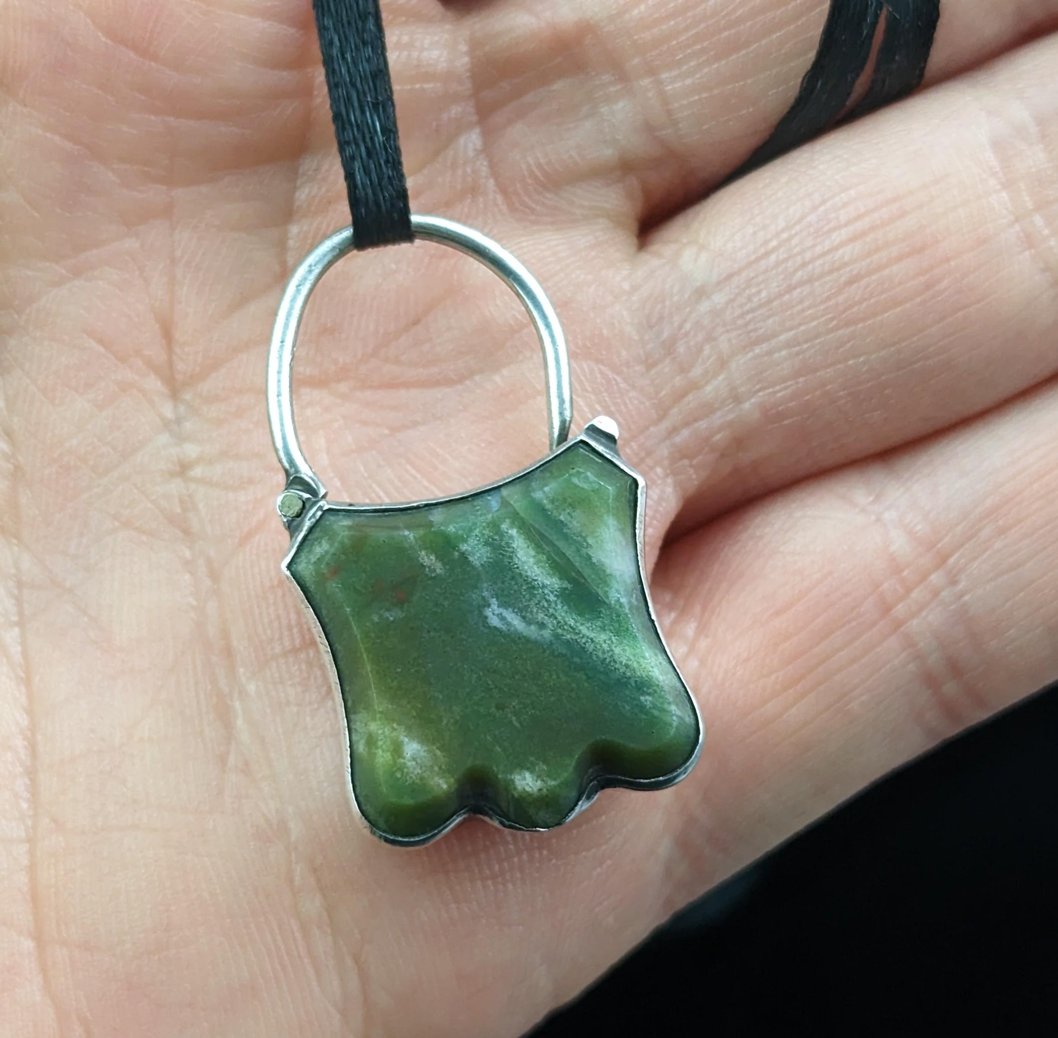 A charming antique sterling silver and green jasper padlock pendant.

This is a beautifully designed piece, shaped as a shield, one side delicately engraved in the aesthetic manner and the other featuring a rich green jasper cut into a shield shape