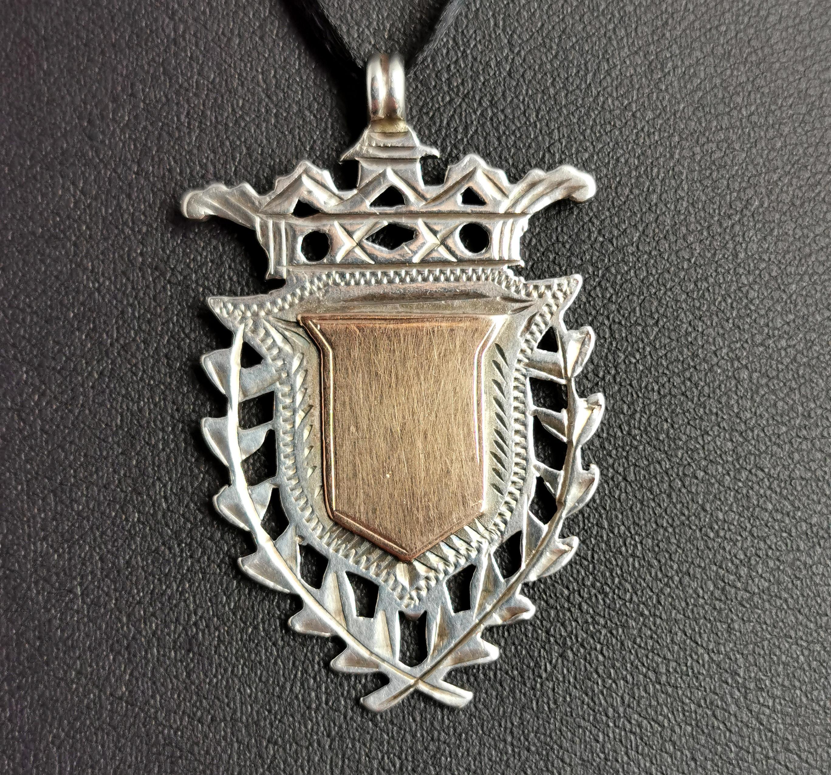 An attractive antique, Edwardian sterling silver and Rose gold shield fob.

A nice heavy fob with a decorative shield design and a 9ct Rose gold cartouche to the centre, this has not been monogrammed or engraved so could be personalised if