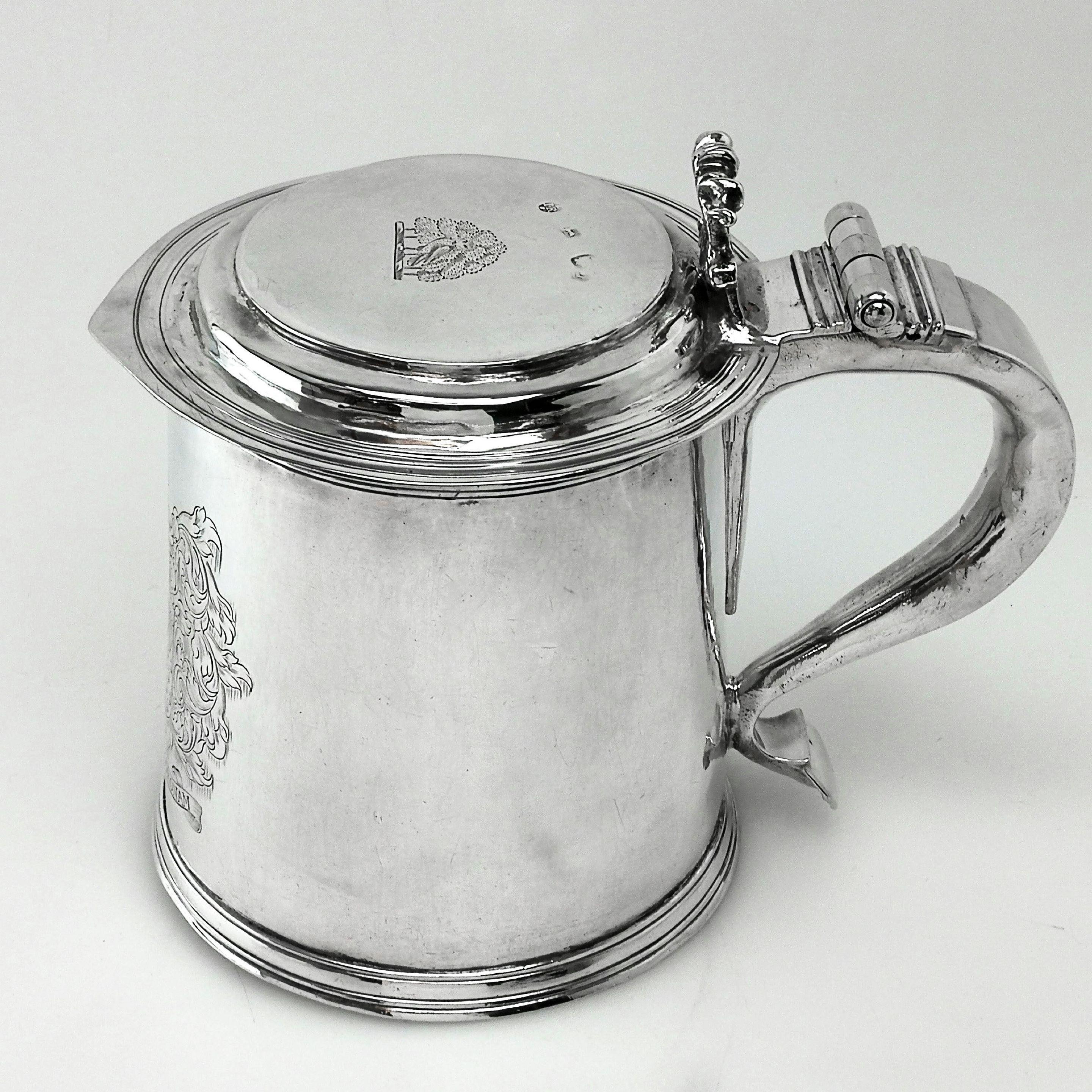 A magnificent Charles II antique solid silver lidded tankard with an elegant tapering straight sided body and featuring and large engraved armorial on the side. The tankard has a hinged lid with a small crest engraved in the centre and a scroll