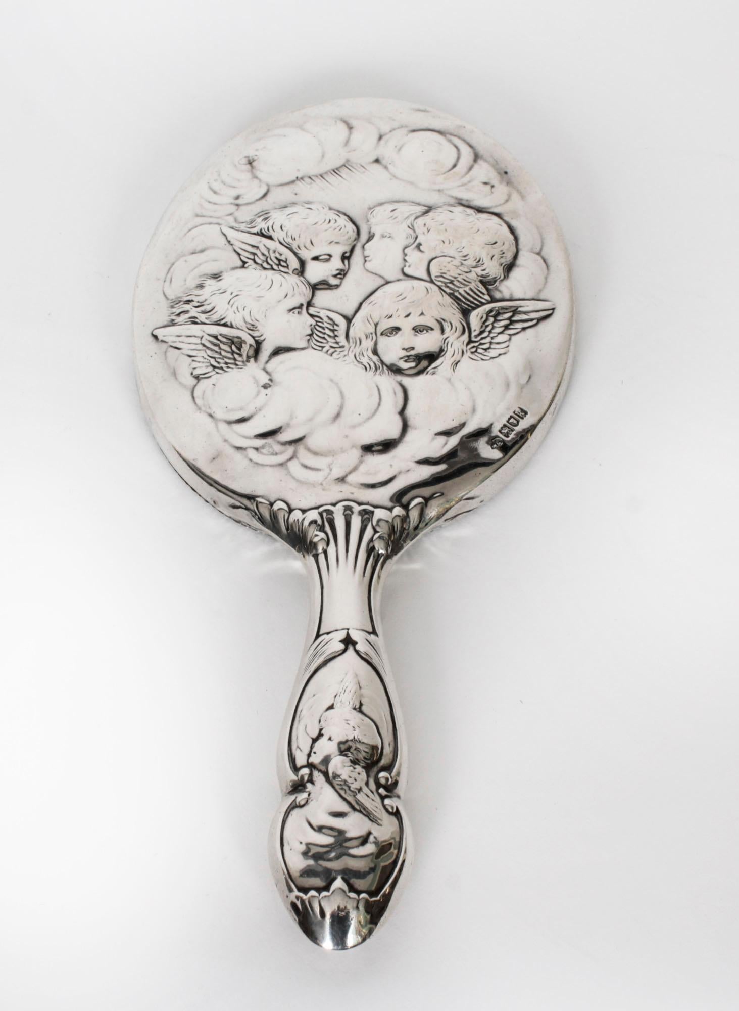 This is a stunning English antique silver hand mirror with hallmarks for London 1905 and the makers mark of the renowned silversmith William Comyns and Sons.
 
The mirror features oval bevelled glass with a beaded rim and is decorated with repousse