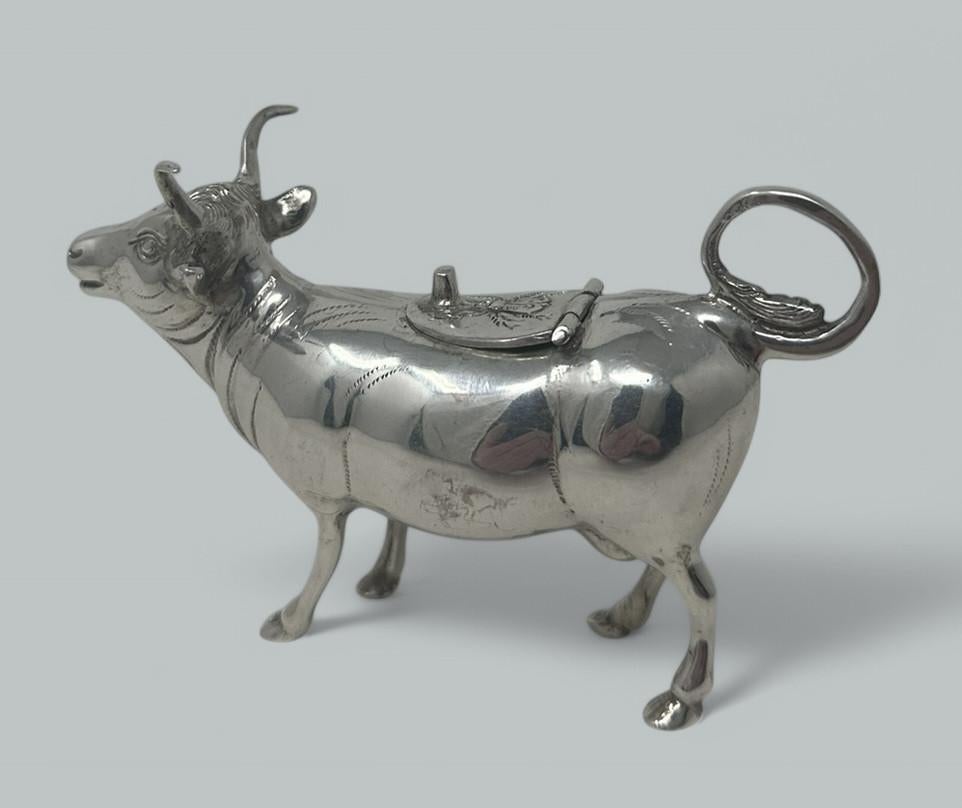 An exceptionally fine quality example of an Edwardian Continental Sterling Silver naturalistic Cow Creamer of small proportions.

The hinged saddle lid with foliate and floral decoration, with the circular tail forming its handle.

Mark of Hanau,