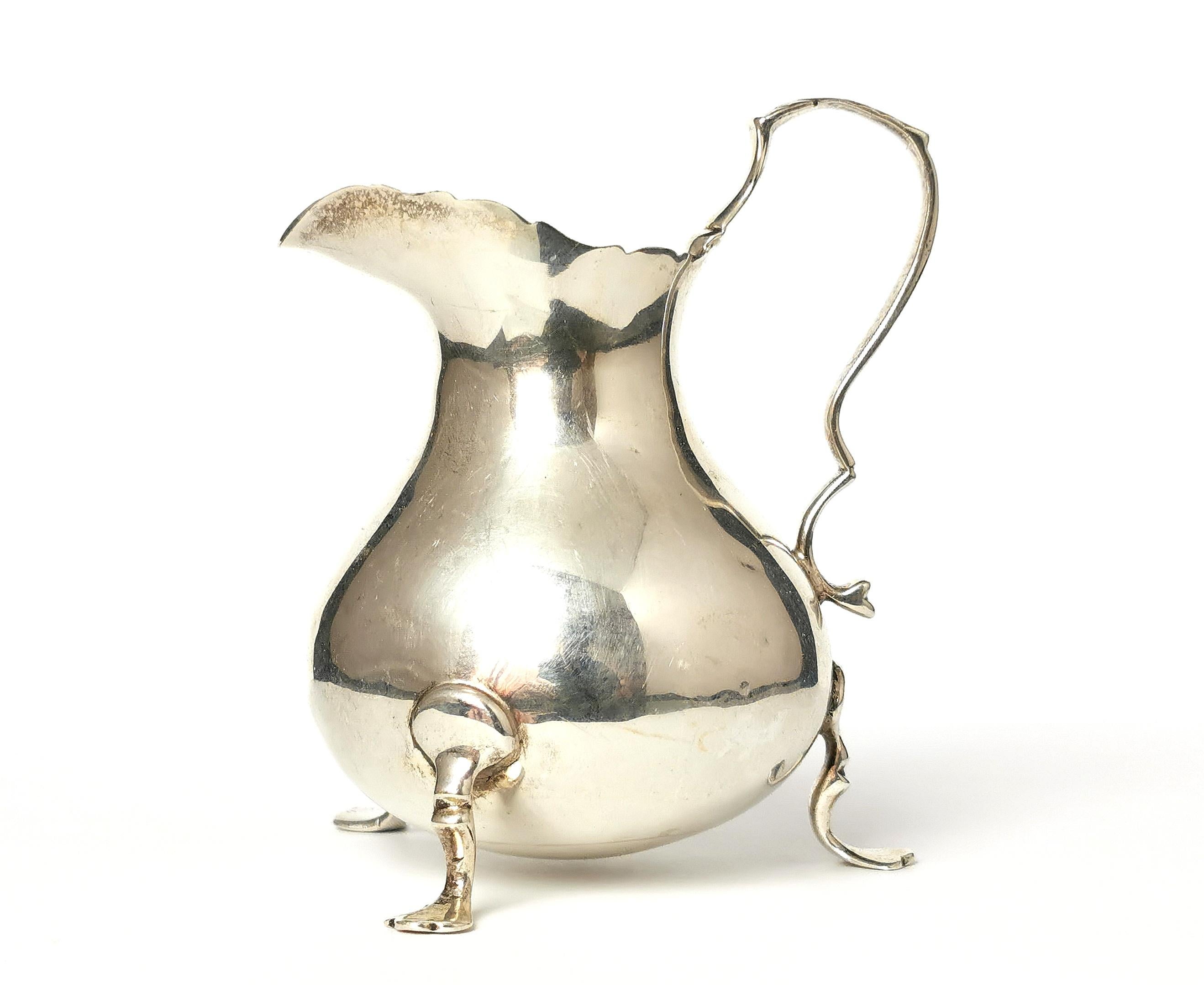 A beautiful antique sterling silver Creamer or milk jug.

This sweet antique Creamer stands on three paw feet and has a squat, pot bellied body which tapers up to the lightly wavy spout.

It has a fine silver handle with a minimalist arrow
