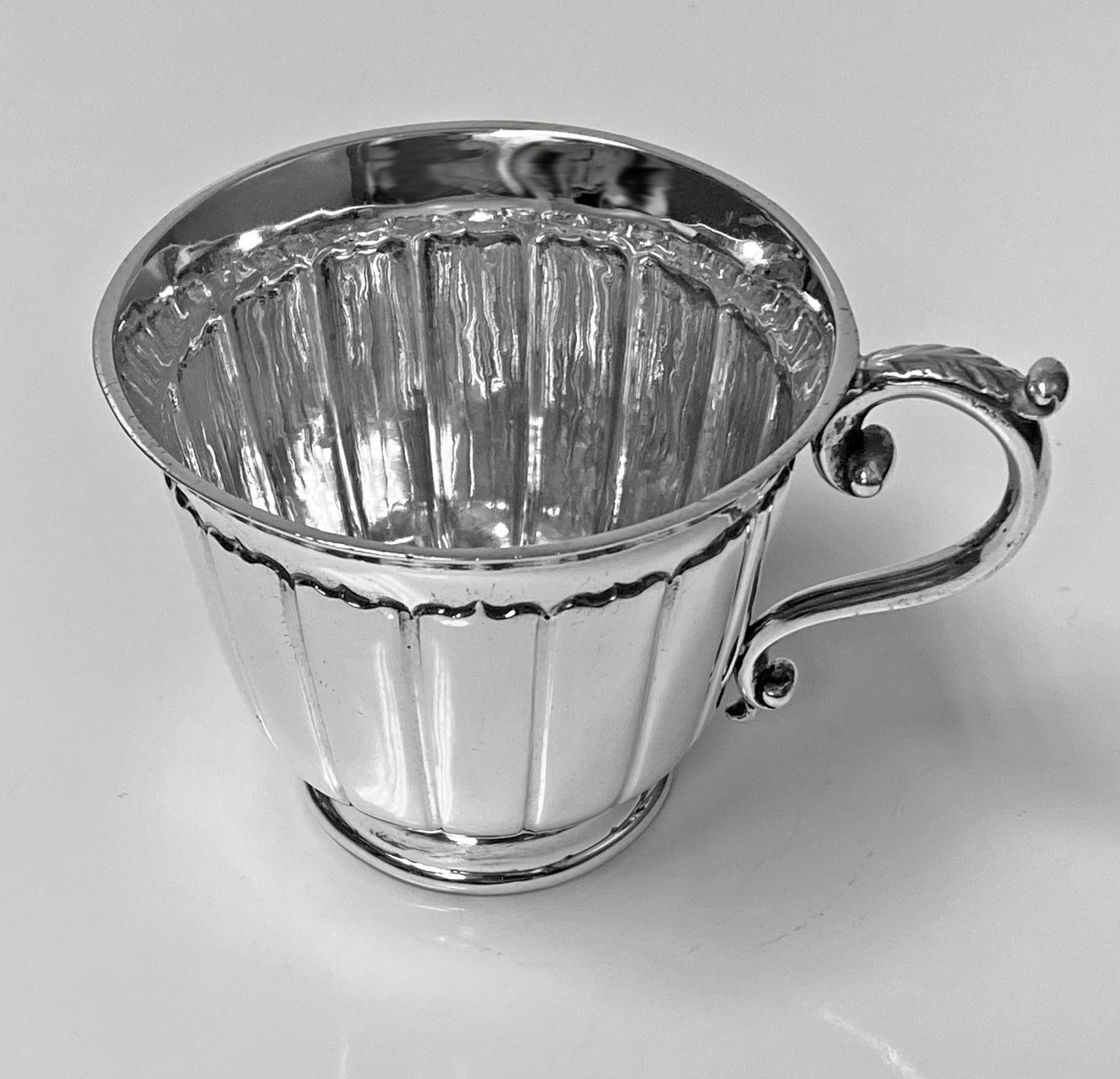 Antique sterling silver cup, London 1909 by William Comyns. The heavy gauge silver cup with panel surround, everted rim, foliate capped scroll handle. Fully hallmarked under base. Measures: Height 2.75 inches, width 4.125 inches. Item weight: 150