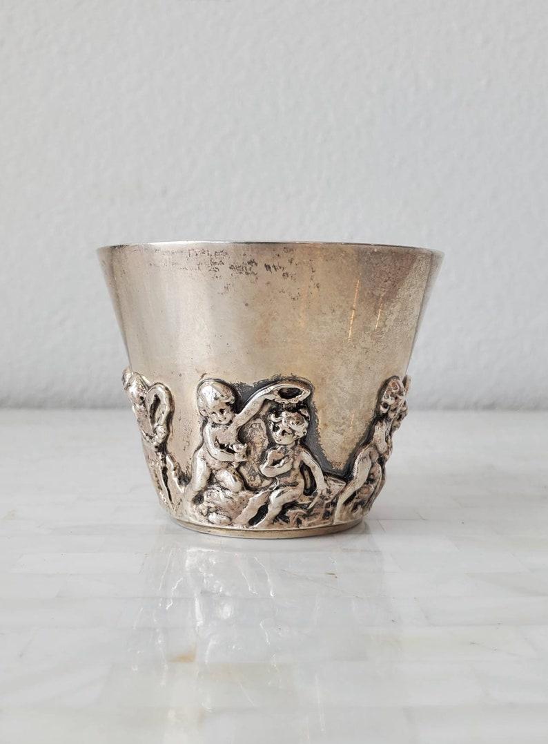 A sterling silver cup with putti at play in relief encircling the cup. Marked on verso with hallmark, 