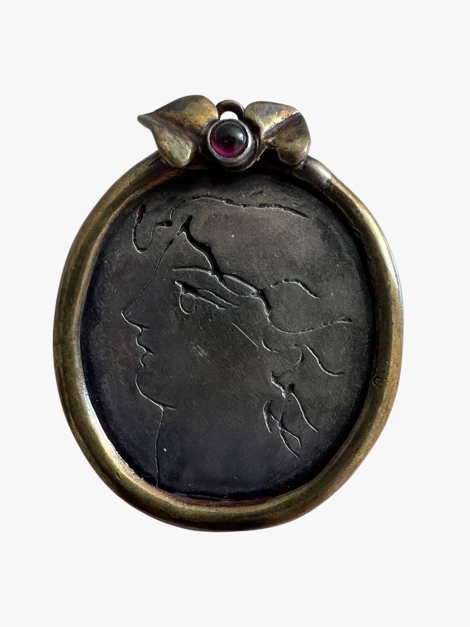 Sterling silver brooch carved with Jean Cocteau intaglio, made from sterling silver. Decorated with garnet cabochon. 
Not signed. 
Silver mark 925. 
Period: 1950s
Condition: good.
Size: 
Width: 3 cm 
Length: 3.9 cm
 
........Additional information