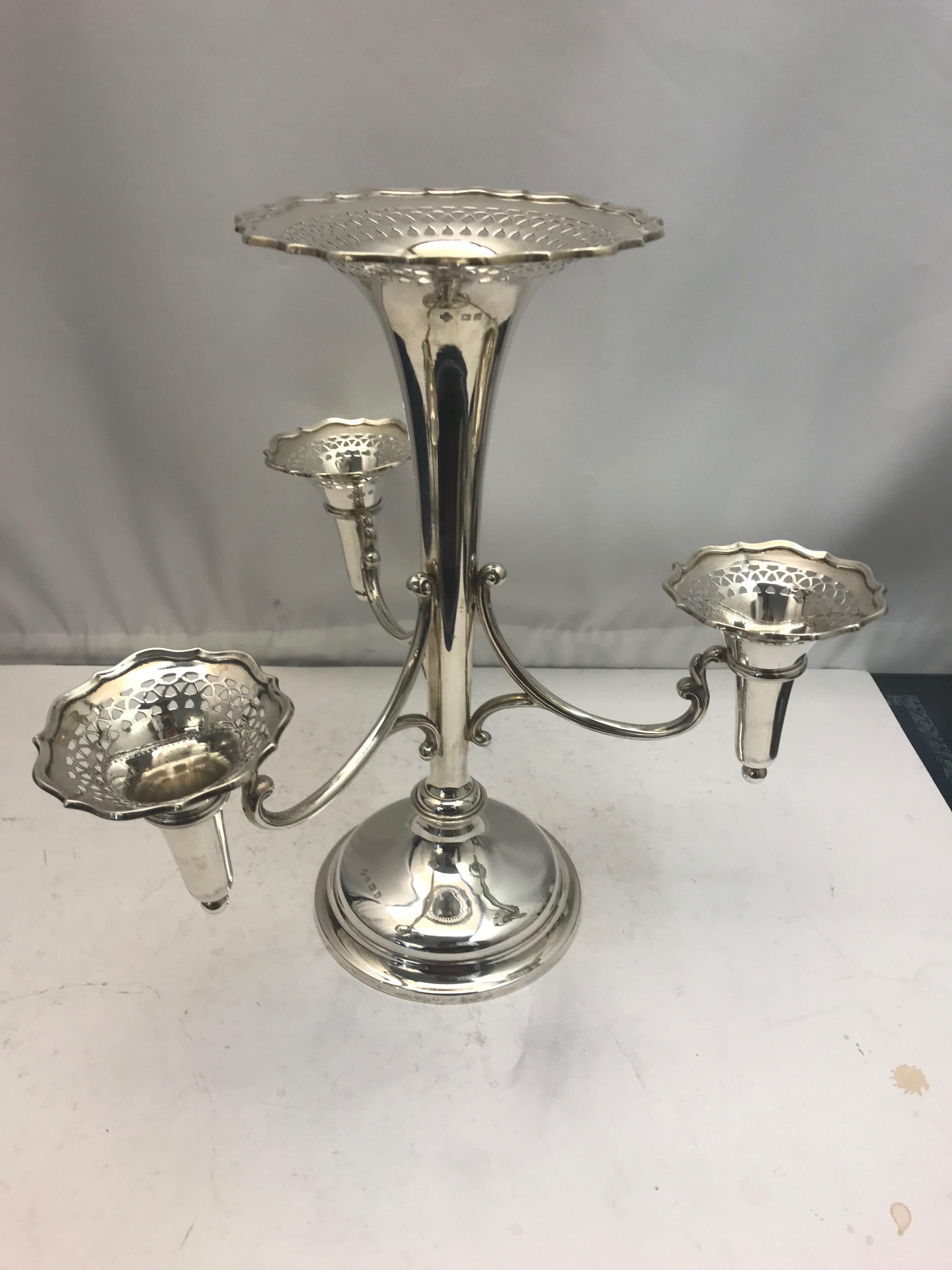 An antique sterling silver flower epergne with one central vase and 3 surrounding it.

Made by Horace Woodward.

Hallmarked on base.

Weight 915 grams.
 