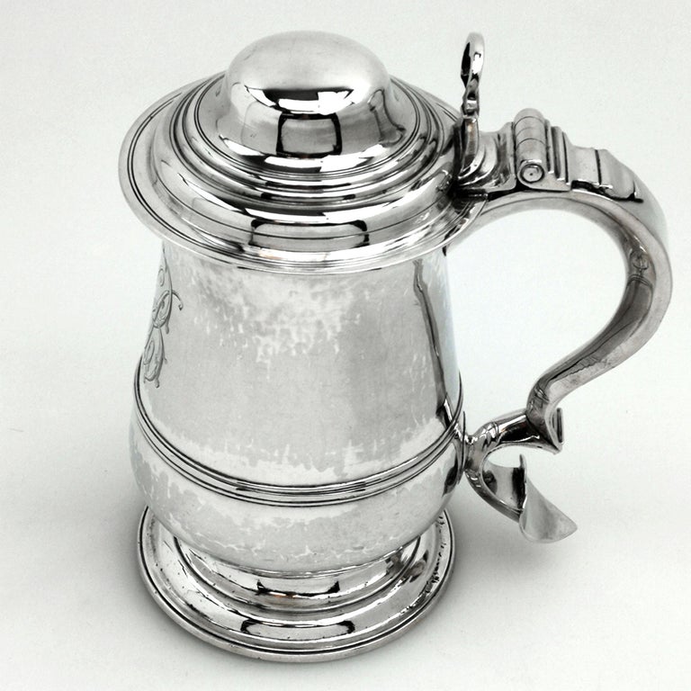 A classic antique George II solid Silver lidded Tankard. This Silver Georgian Quart Tankard has an impressive domed hinged lid with a shaped thumb piece and a substantial scroll handle. The Tankard Mug has a traditional baluster shape with an