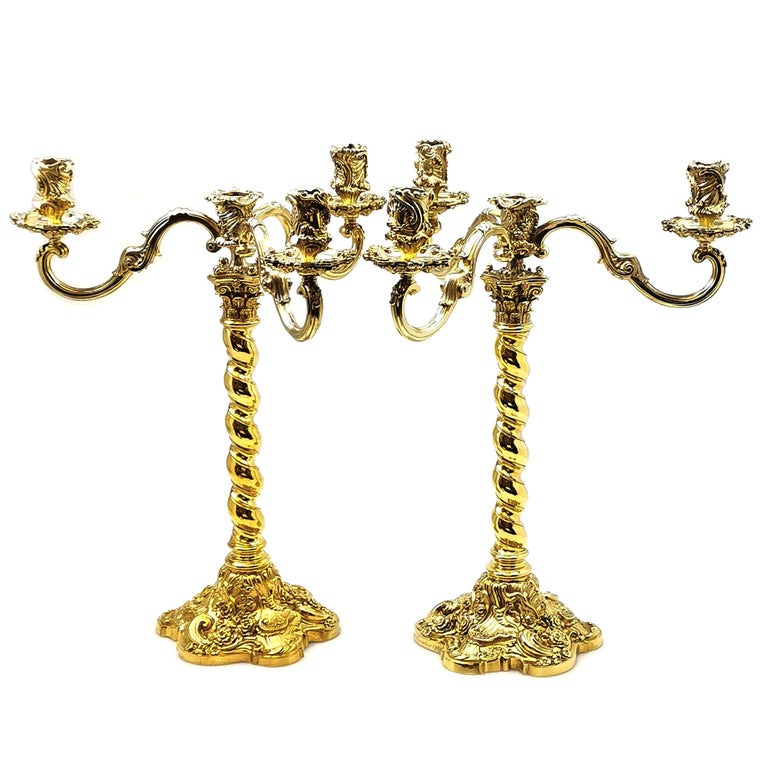 A magnificent pair of Antique Silver Gilt Candelabra. These Candelabra stand on impressive chased bases featuring Rococo style shell, scroll and floral patterning. The Candlesticks have a barley twist column with a Corinthian Capital. The Candelabra