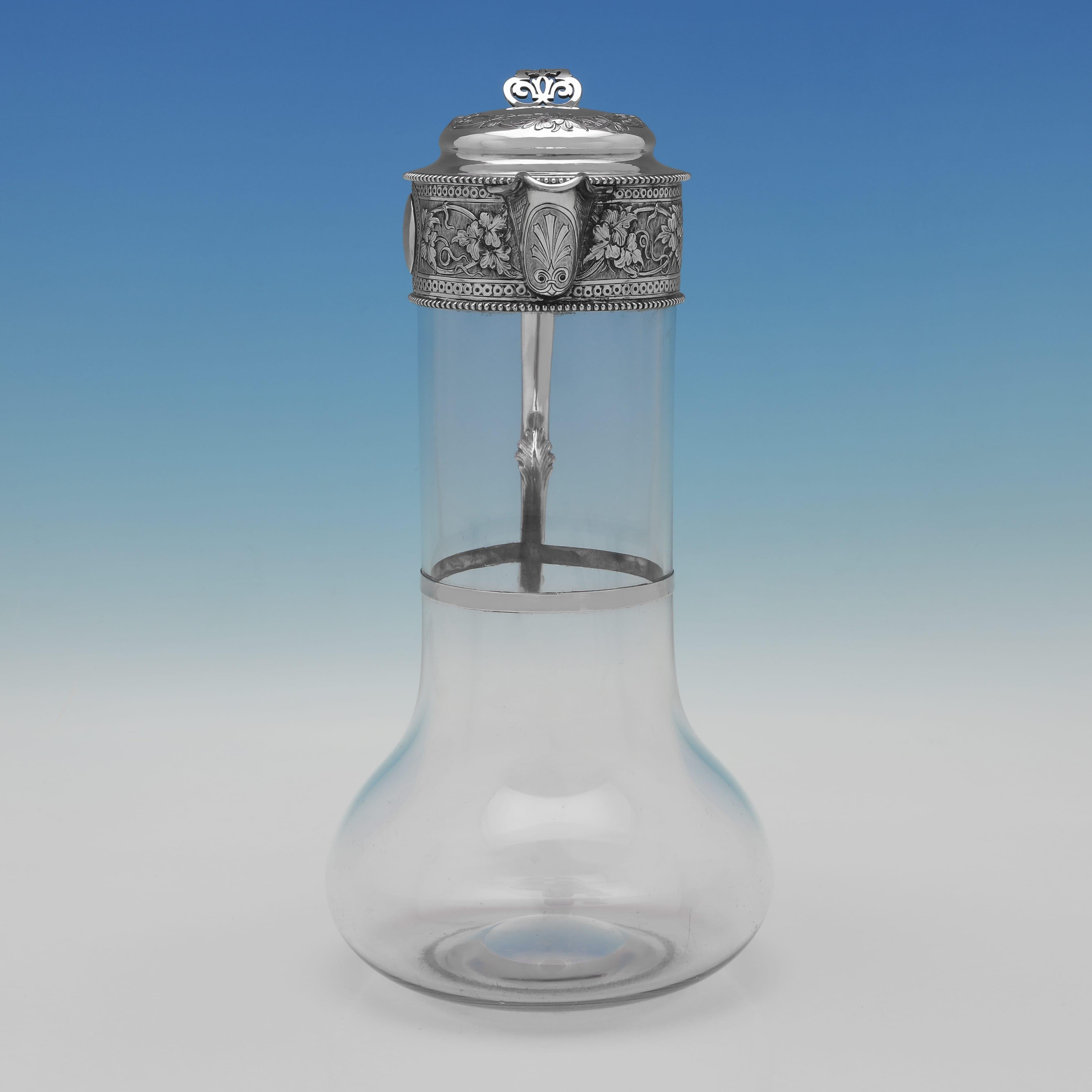 Dieser dekorative, überdurchschnittlich hohe Krug aus antikem Sterlingsilber und Glas wurde 1891 in Sheffield von William George Sissons gepunzt. Er hat eine ziselierte Fassung aus Ranken und Blumen, einen mit Perlen verzierten Ausguss und einen