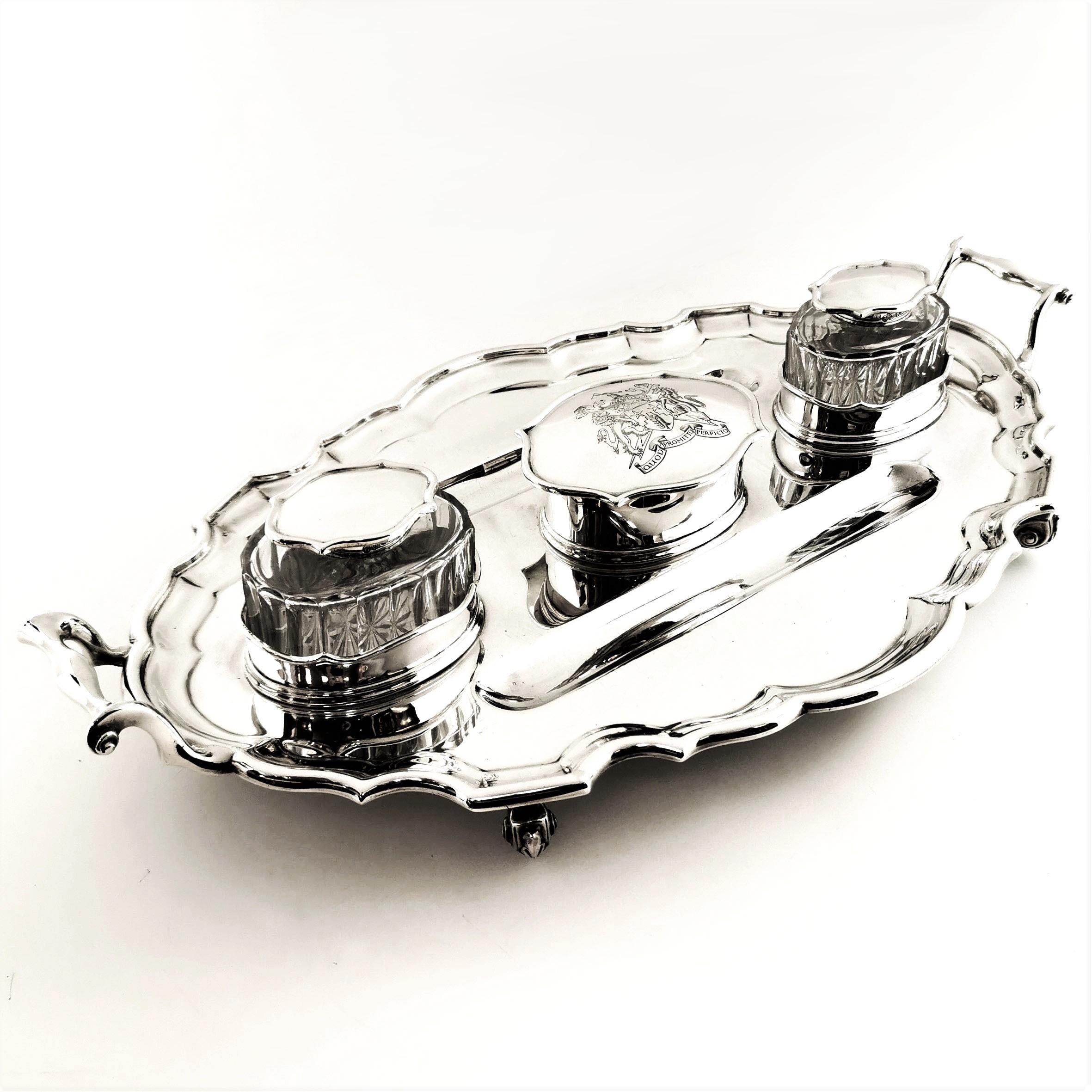 An impressive oval Antique solid Silver Inkstand standing on four scroll feet with a shaped rim and two scroll handles. The Inkstand has a pair of fitted Glass Inkwells with Solid Silver collars and hinged lids. There is a central lidded container