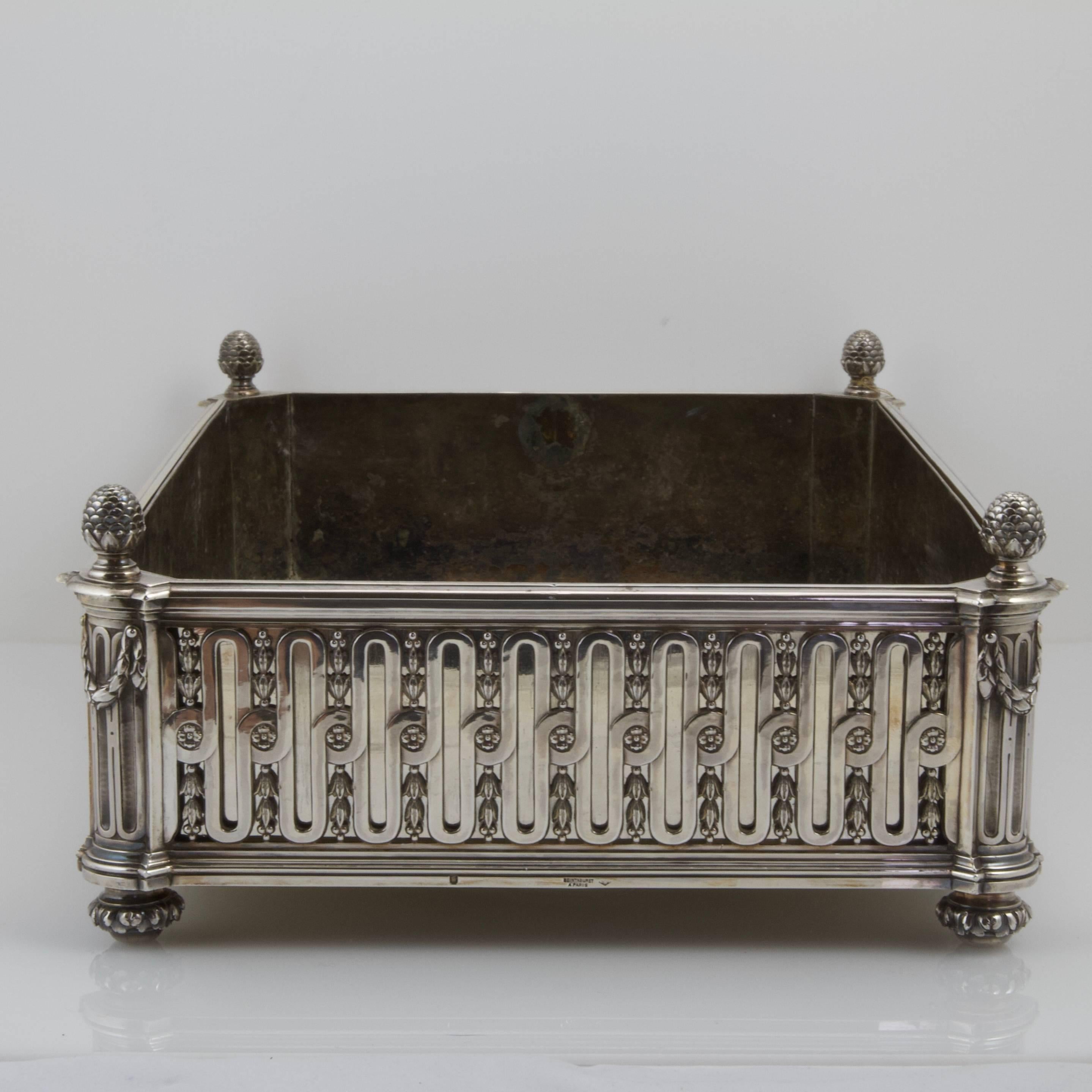 Rectangular sterling silver jardiniere entirely with a neo-classical cannelure pattern intersperced with acanthus frise. Bordered on each corner with a pine cone. Rested on four round feet decorated with acanthus leaves.
Signature and maker's mark