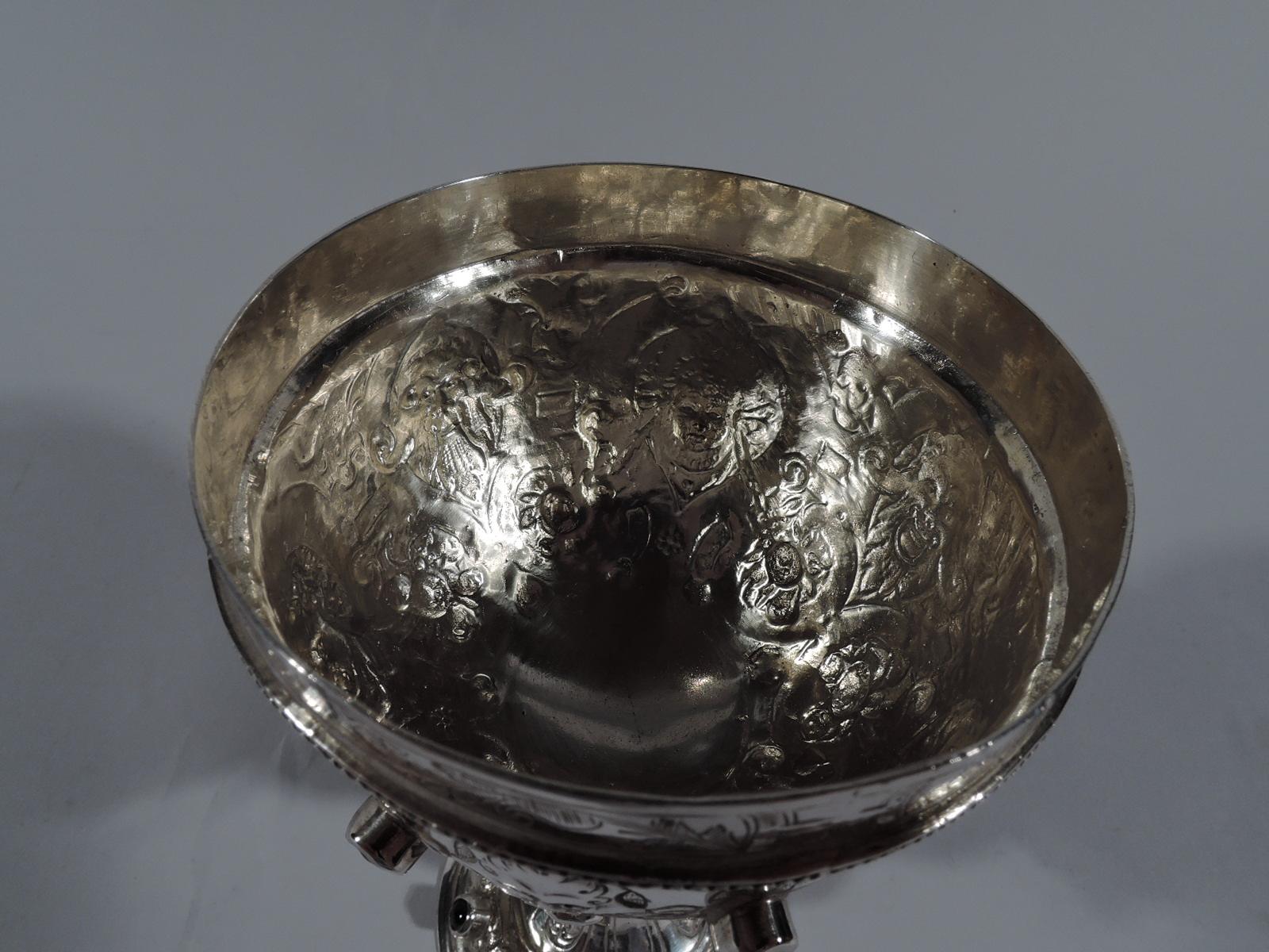 Jeweled sterling silver goblet. Imported to England in 1900 by James Swann. Round bowl on baluster stem on domed foot. Chased and engraved Classical masks in Strapwork frames as well as scrolls and flowers. Cabochon jewels in sterling silver mounts,
