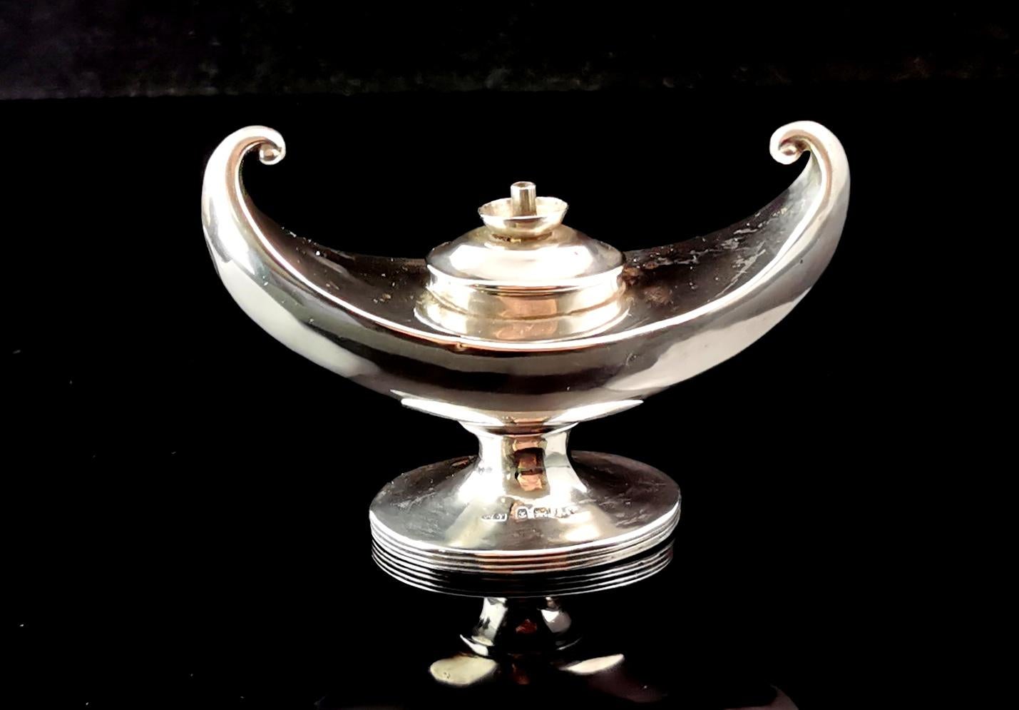 A stylish Antique Art Deco era sterling silver lamp form table lighter.

An unusual genie style lamp curved at both ends with an elongated boat shape.

It has a smooth polished finish and a lift out lid.

Designed to be used with a liquid fuel and