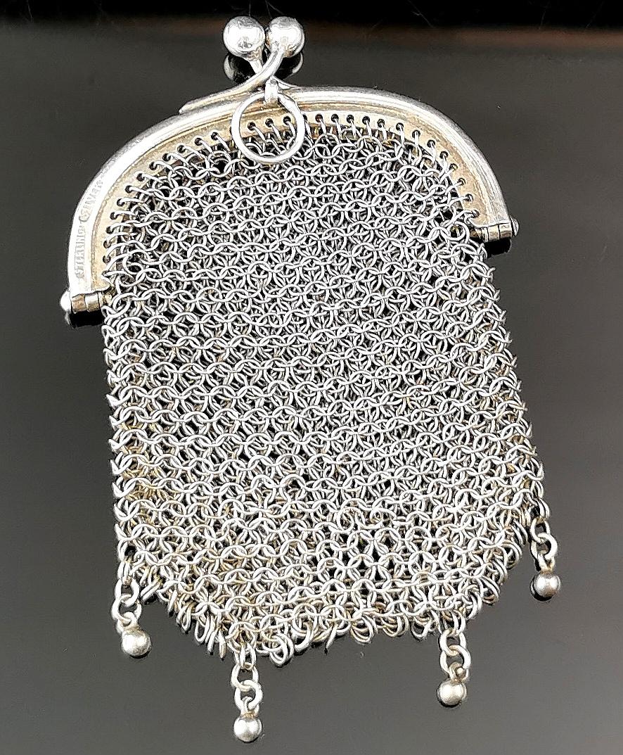 A stunning antique sterling silver coin purse.

The body is made up from intricately woven and delicate sterling silver mesh with fine detailing.

The base of the purse features a four beaded fringe and it has a plain silver frame with a kiss lock