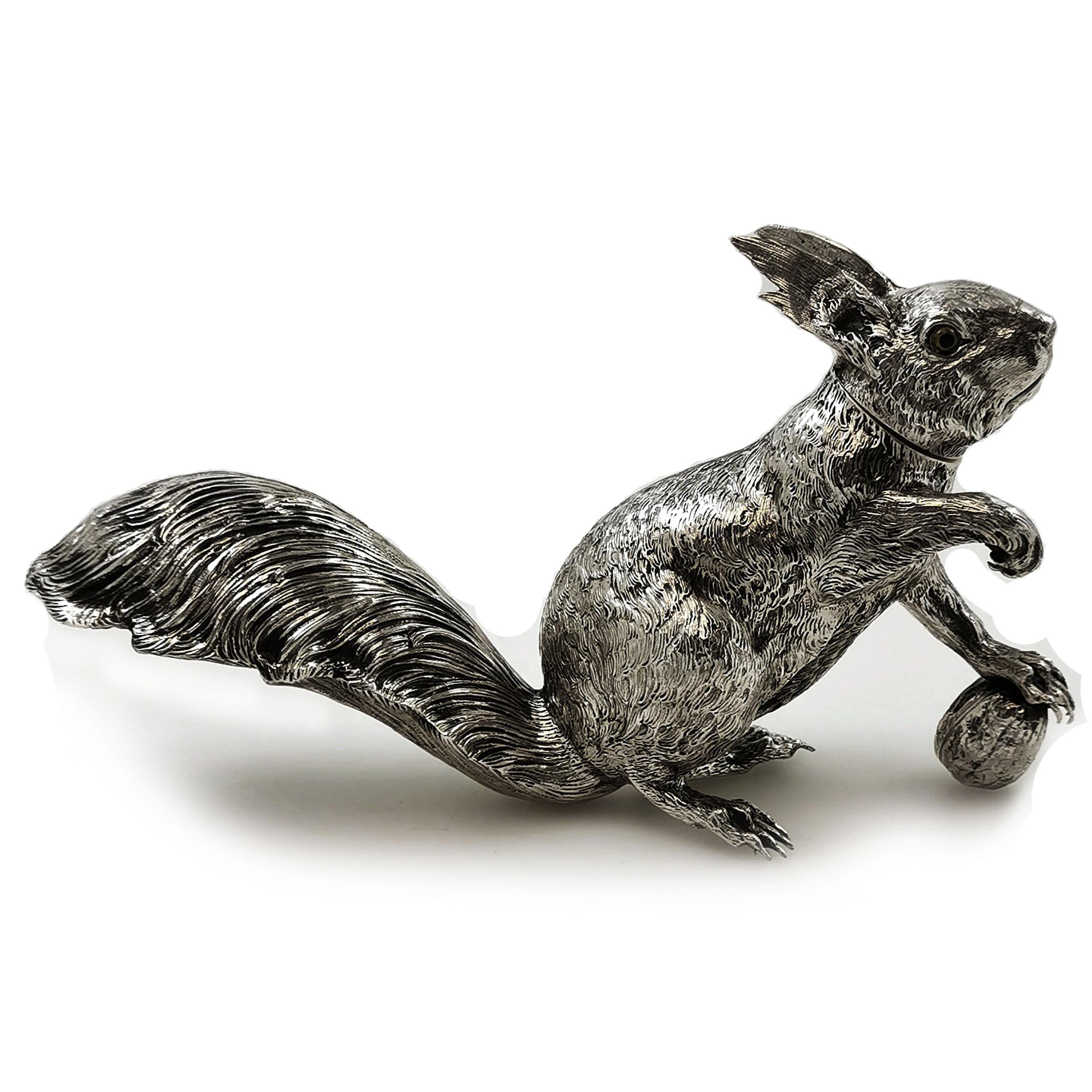 A gorgeous Antique German Solid Silver model Squirrel standing with his one paw resting on a nut and the other raised in the air. The Squirrel has a full busy tail and splendid ears. The Squirrel has inset yellow and black glass eyes. This Figure of