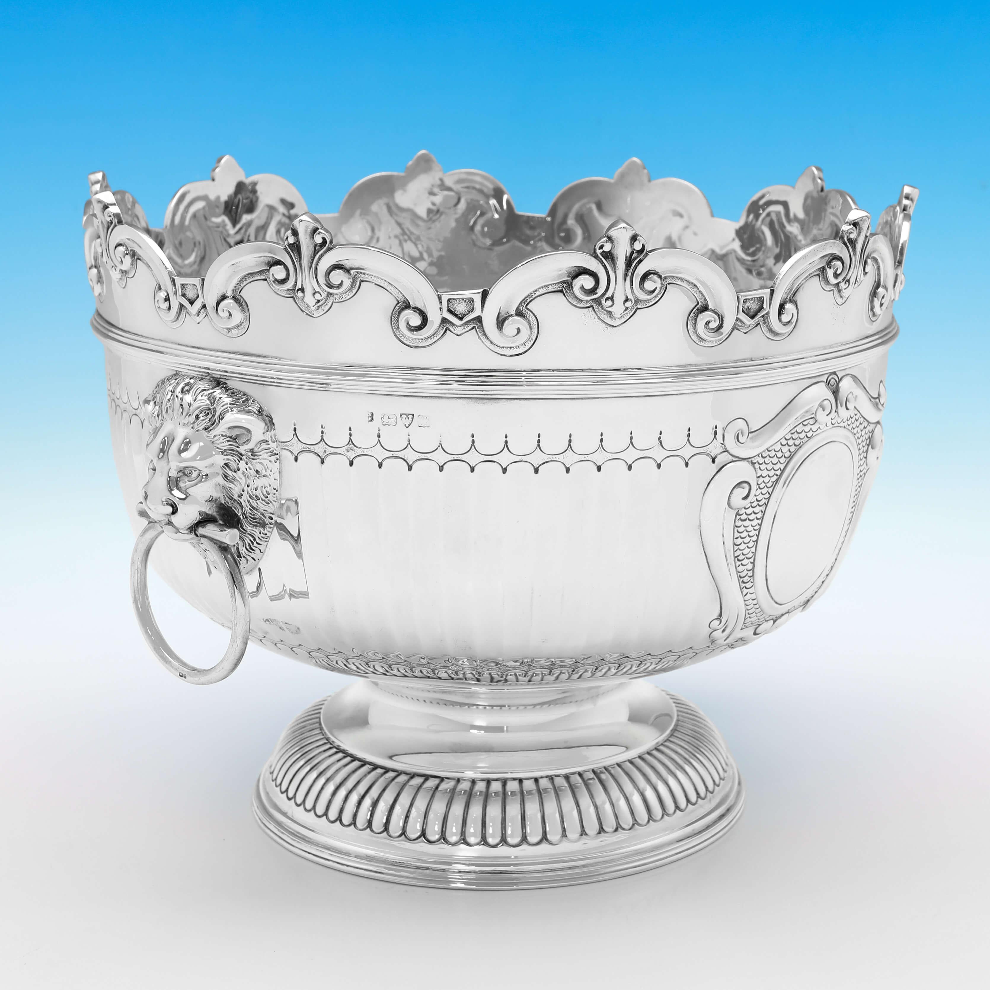 Hallmarked in Chester in 1911 by Nathan & Hayes, this attractive, Antique Sterling Silver Bowl, is in the Montieth style, with a shaped and scalloped rim, drop ring lion mask handles, and flat chasing to the body. 

The bowl measures 9.5