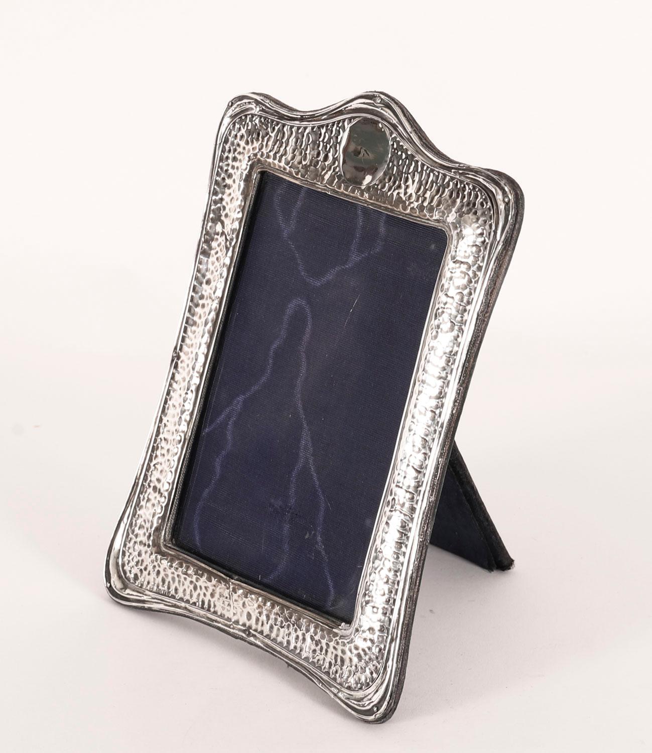 A superb Antique Edwardian decorative sterling silver photo frame by Henry Mathews, Birmingham 1905.
 
Beautiful portrait rectangular frame decorated with with hammered finish a vacant cartouche pediment and a blue velvet easel back.

An excellent