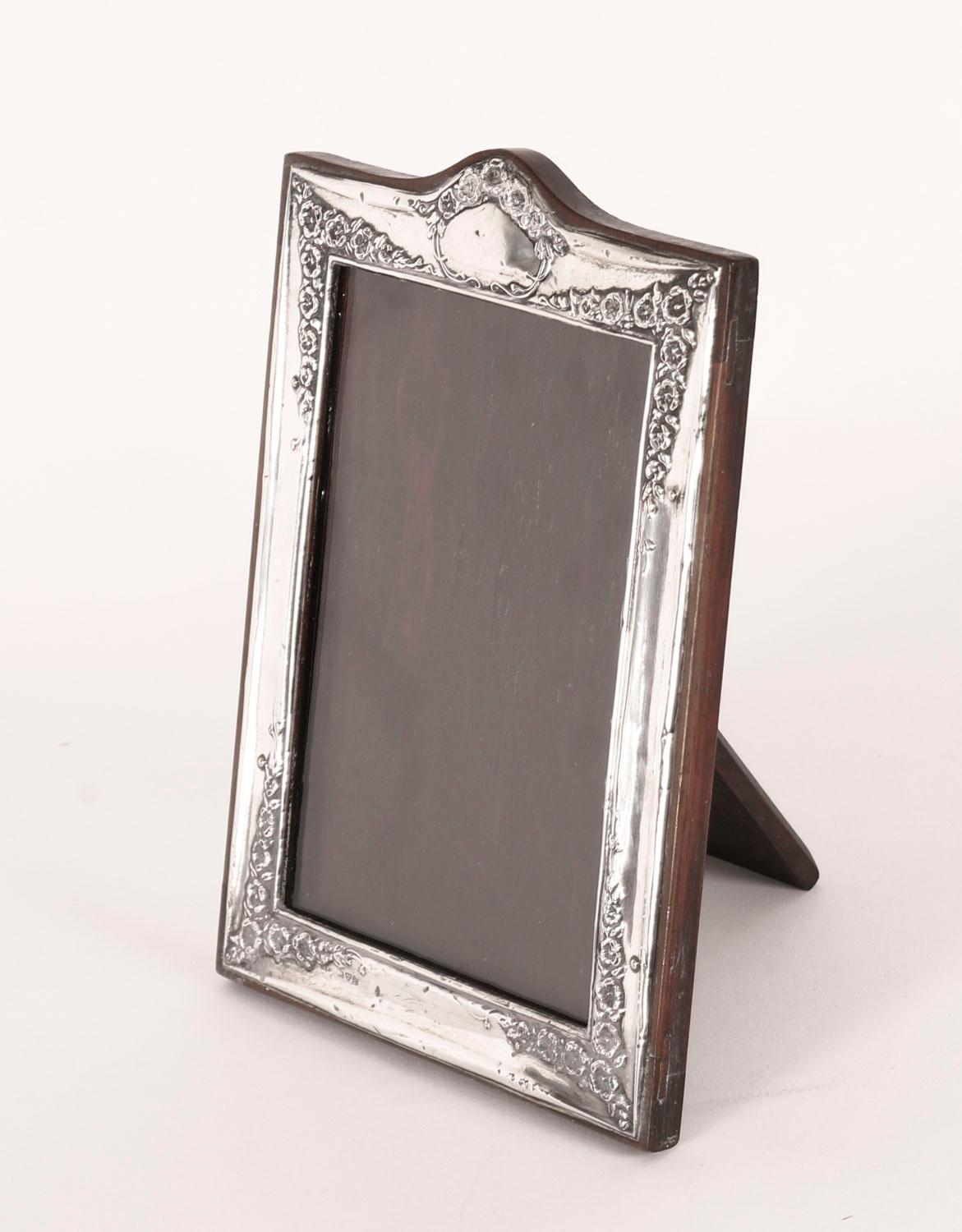 A superb decorative antique sterling silver photo frame by J R F Ltd London, late 19th century in date.

Beautiful portrait rectangular frame decorated with trailing blue bells to the corners, a vacant cartouche pediment and with a polished oak