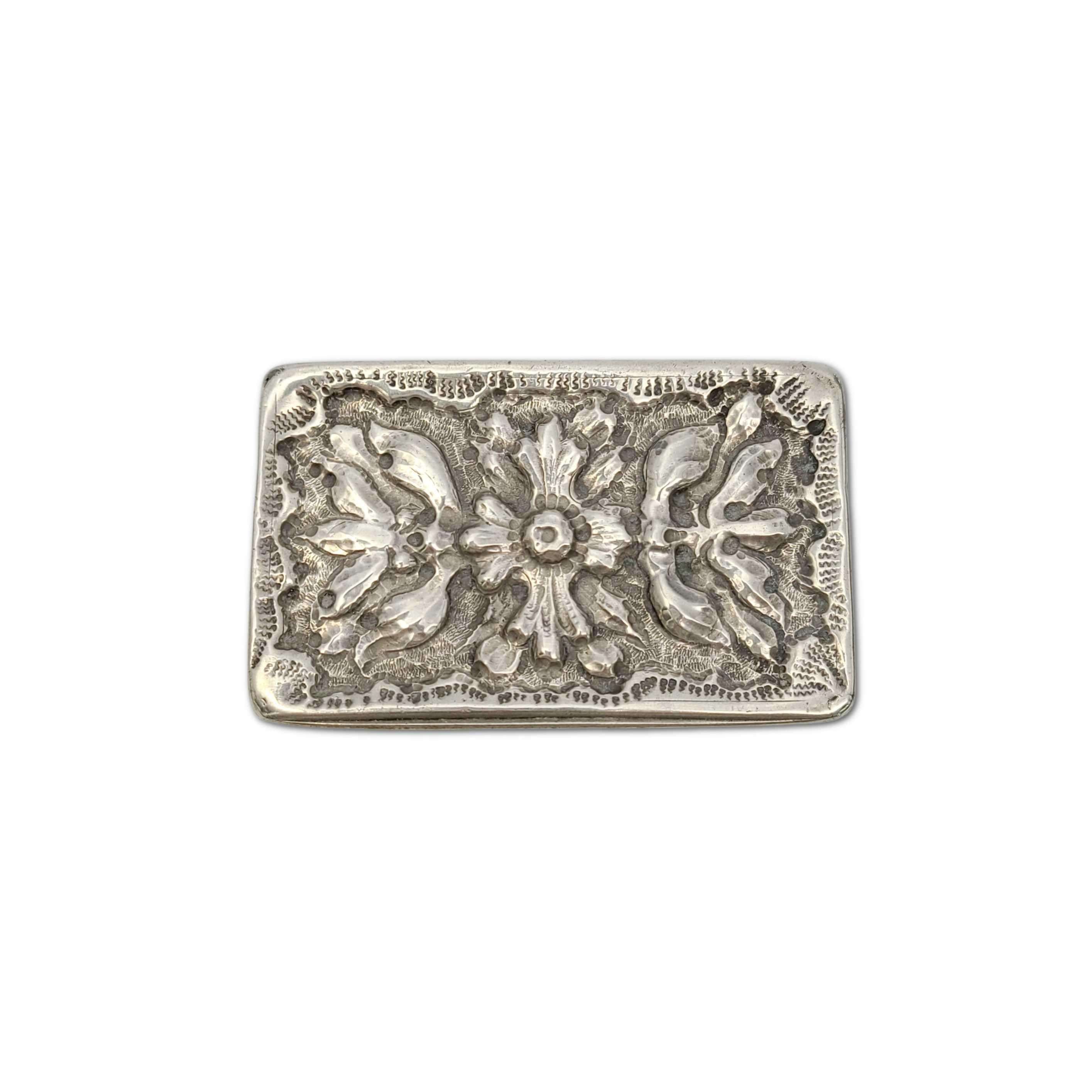 Antique small sterling silver box.

Small, rectangular sterling silver box with repousse flower design on the lid, stamped and etched designs around the box, and a polished smooth bottom.

Measures: approx 3